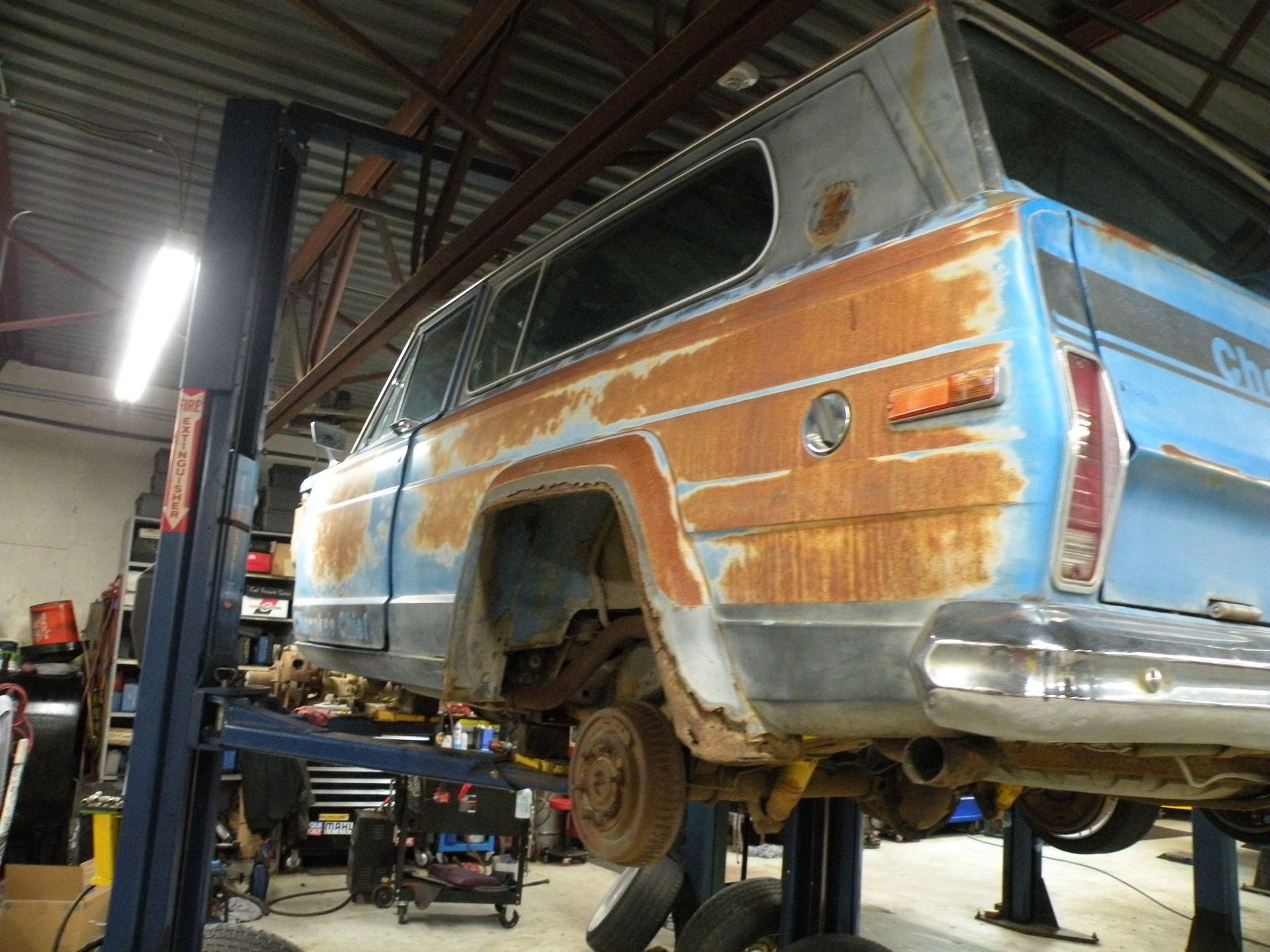 Rusty blue and tan vintage SUV raised on a lift in a garage. | Autobahn Performance Inc