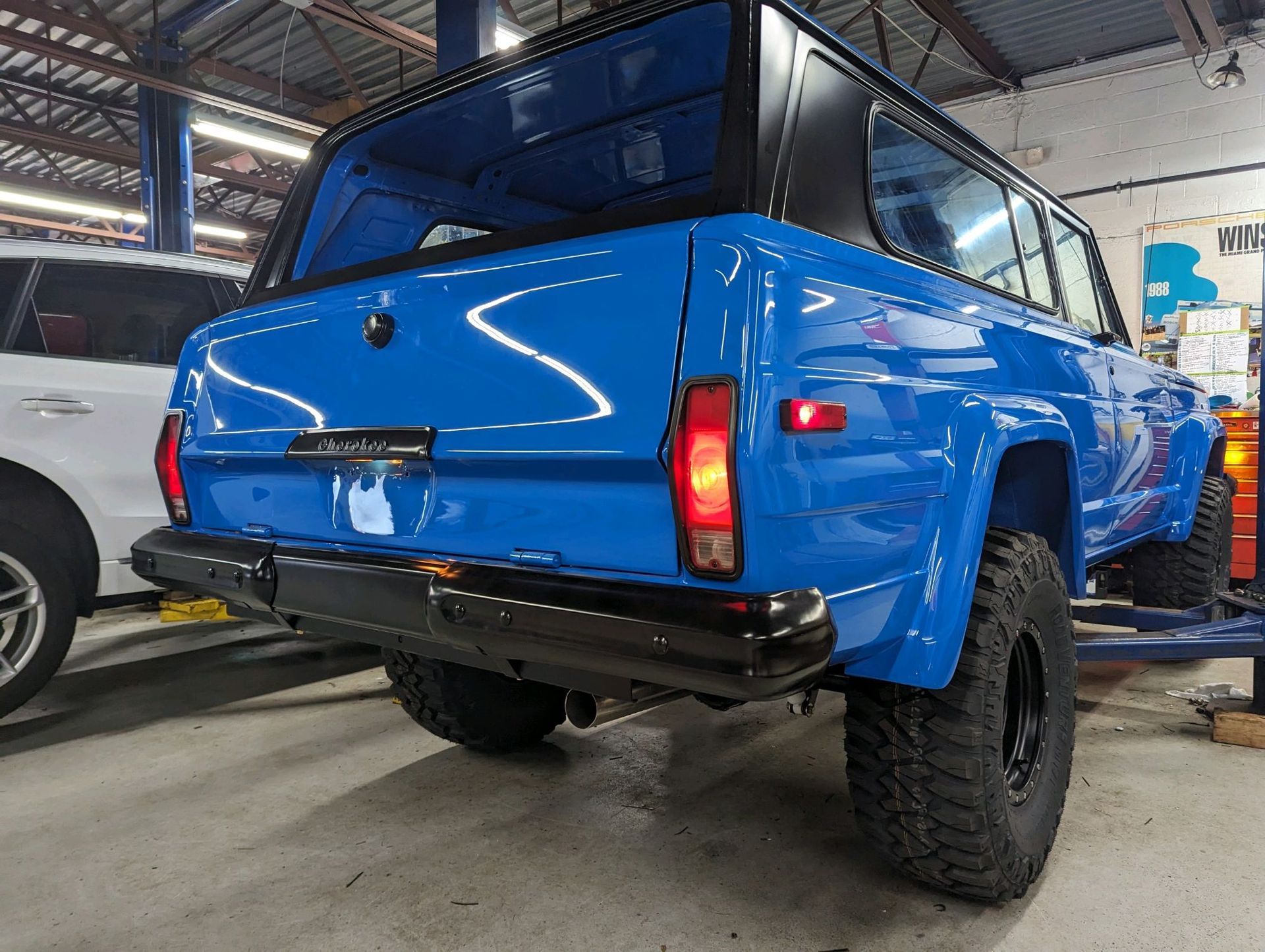 Blue and black Jeep Cherokee with large tires, in a repair shop. | Autobahn Performance Inc