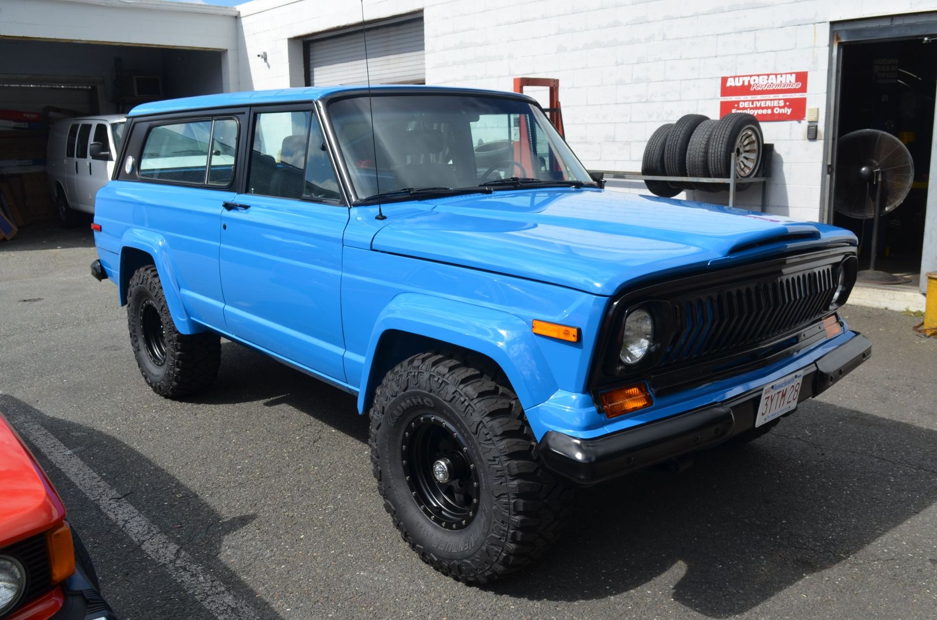 Blue Jeep Cherokee with black wheels and tires parked outside a garage. | Autobahn Performance Inc