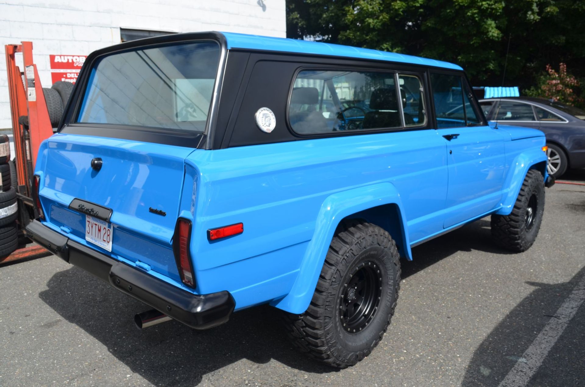 Bright blue vintage Jeep Cherokee with black top and tires, parked outdoors. | Autobahn Performance Inc