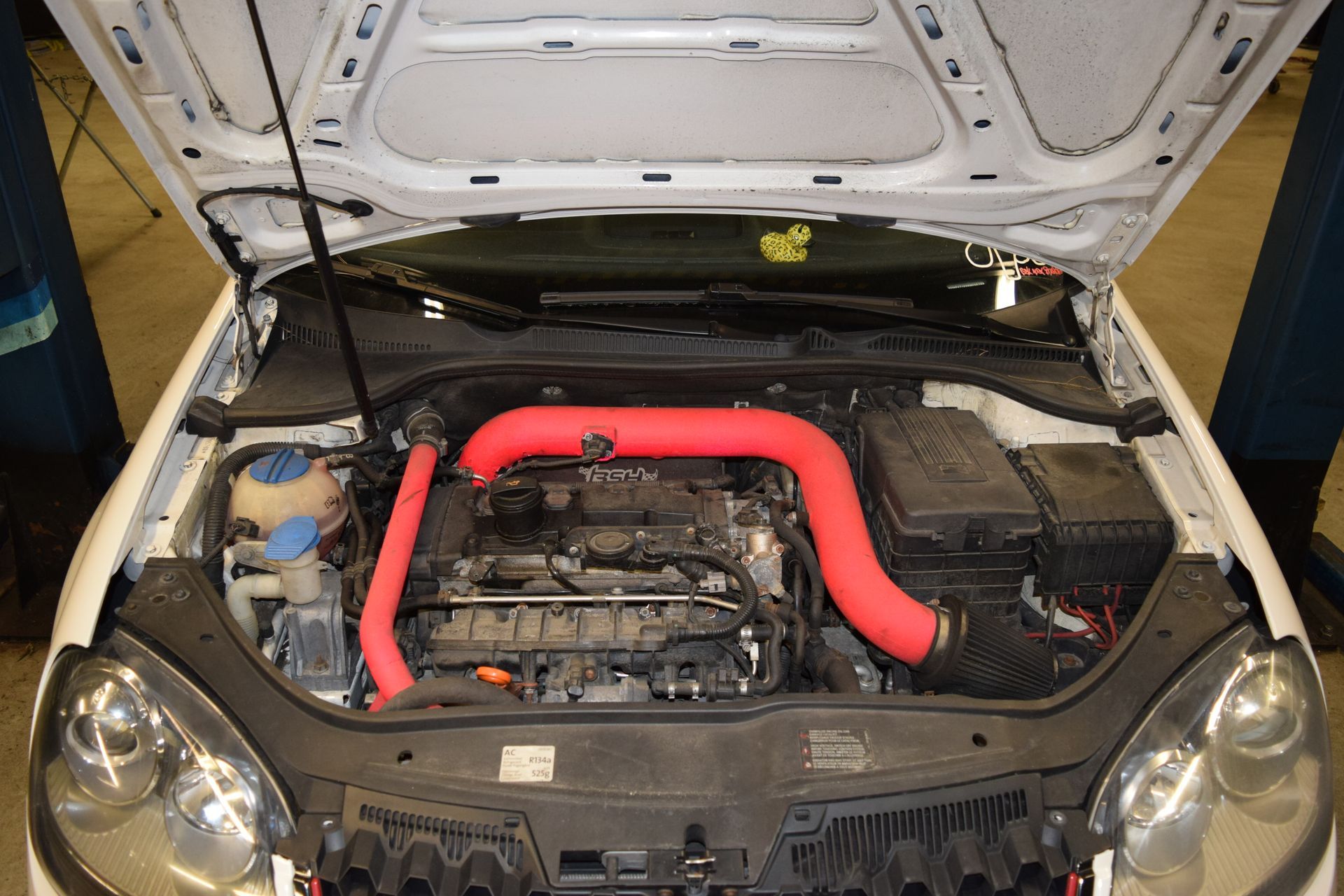 Open white car hood revealing a red intake system. Engine bay is visible. | Autobahn Performance Inc