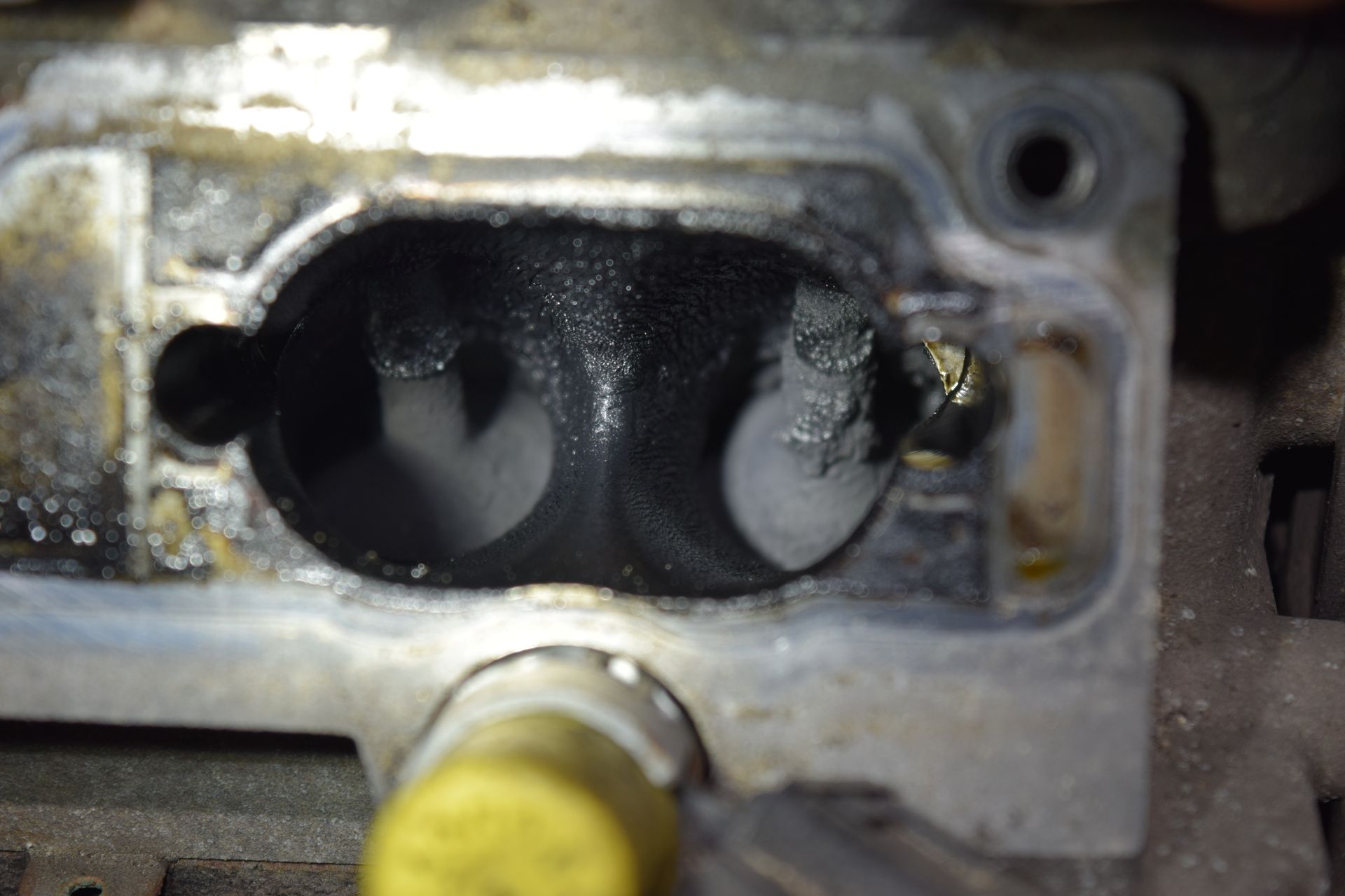 Close-up of a dark, sooty engine port, possibly part of a car's intake manifold. | Autobahn Performance Inc