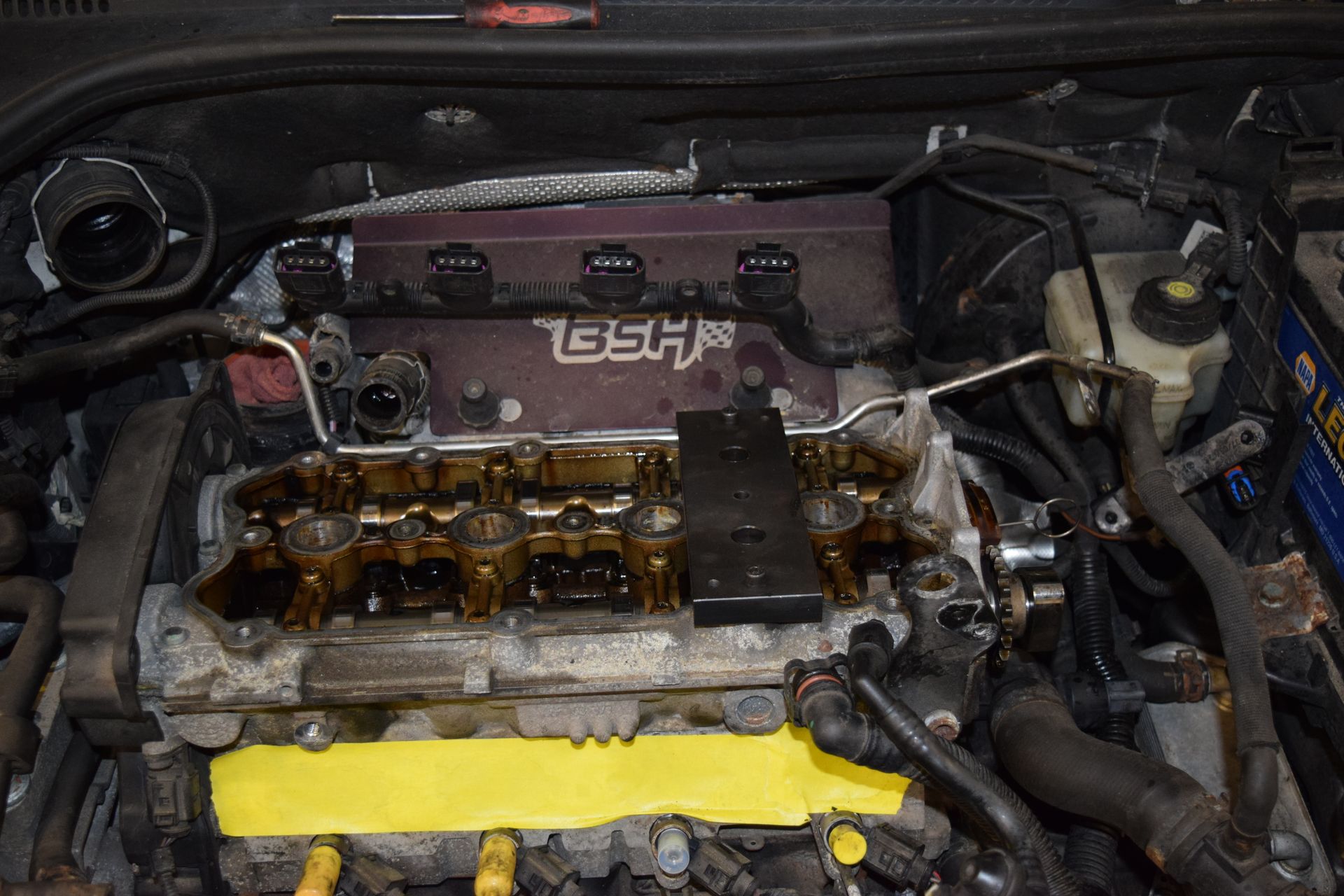 Car engine bay open, showing exposed engine components and a custom BSH cover. | Autobahn Performance Inc