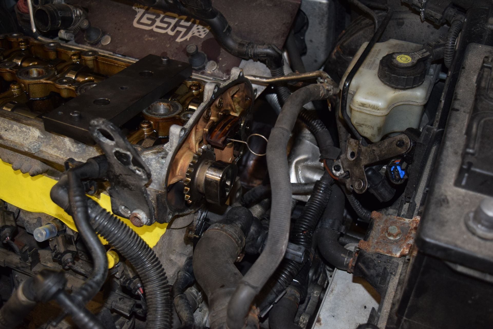 Engine bay with exposed engine components, likely during repair. Oil stains visible. Black hoses and metal parts are prominent. | Autobahn Performance Inc