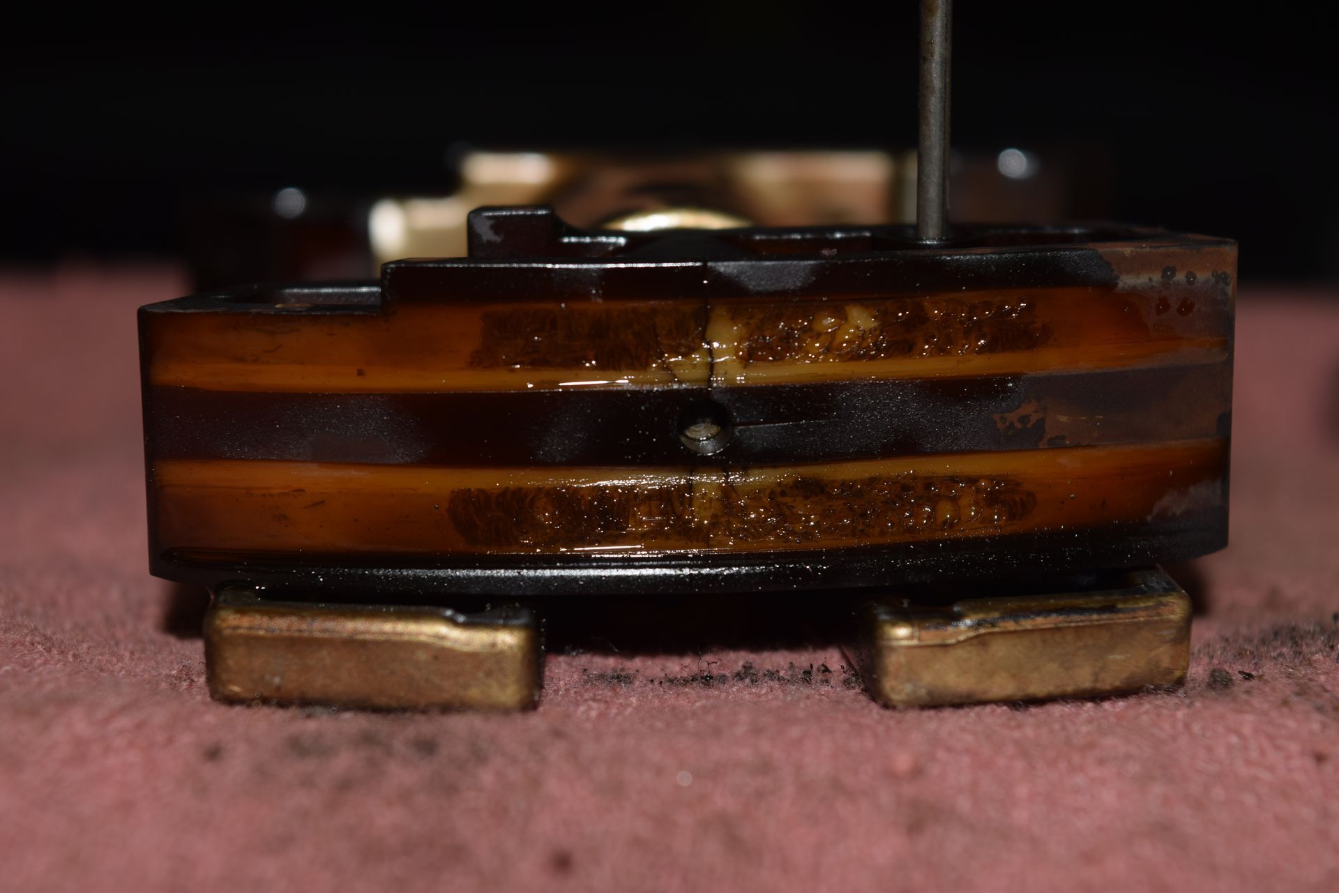 Close-up of a dark, multi-layered mechanical component with brown and gold sections, possibly part of a machine. | Autobahn Performance Inc