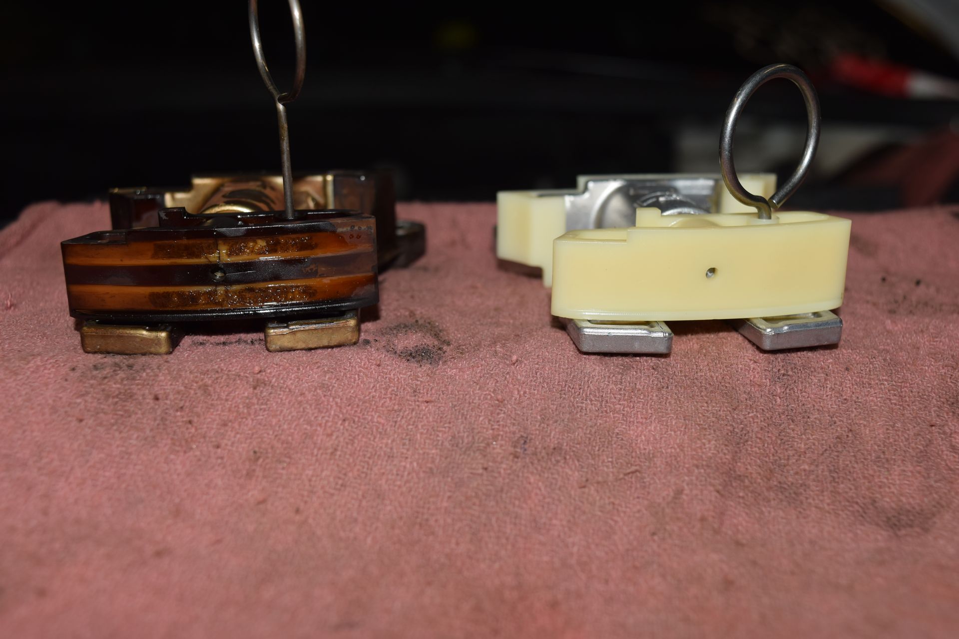 Two automotive parts side-by-side: old, worn oil pump with a new, tan replacement. Both have metal wire loops. | Autobahn Performance Inc