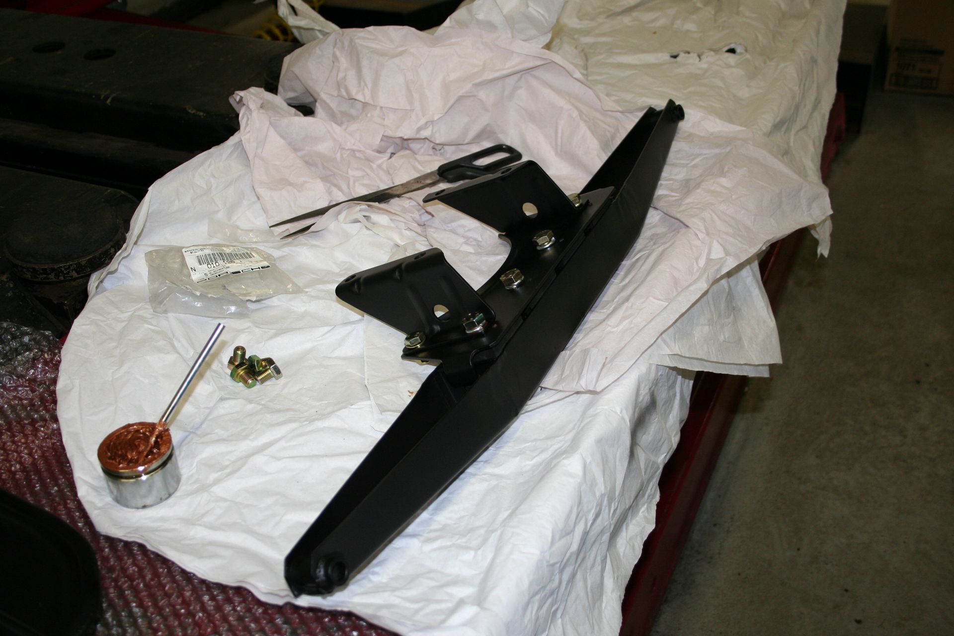 Black car spoiler and mounting hardware on white paper. | Autobahn Performance Inc