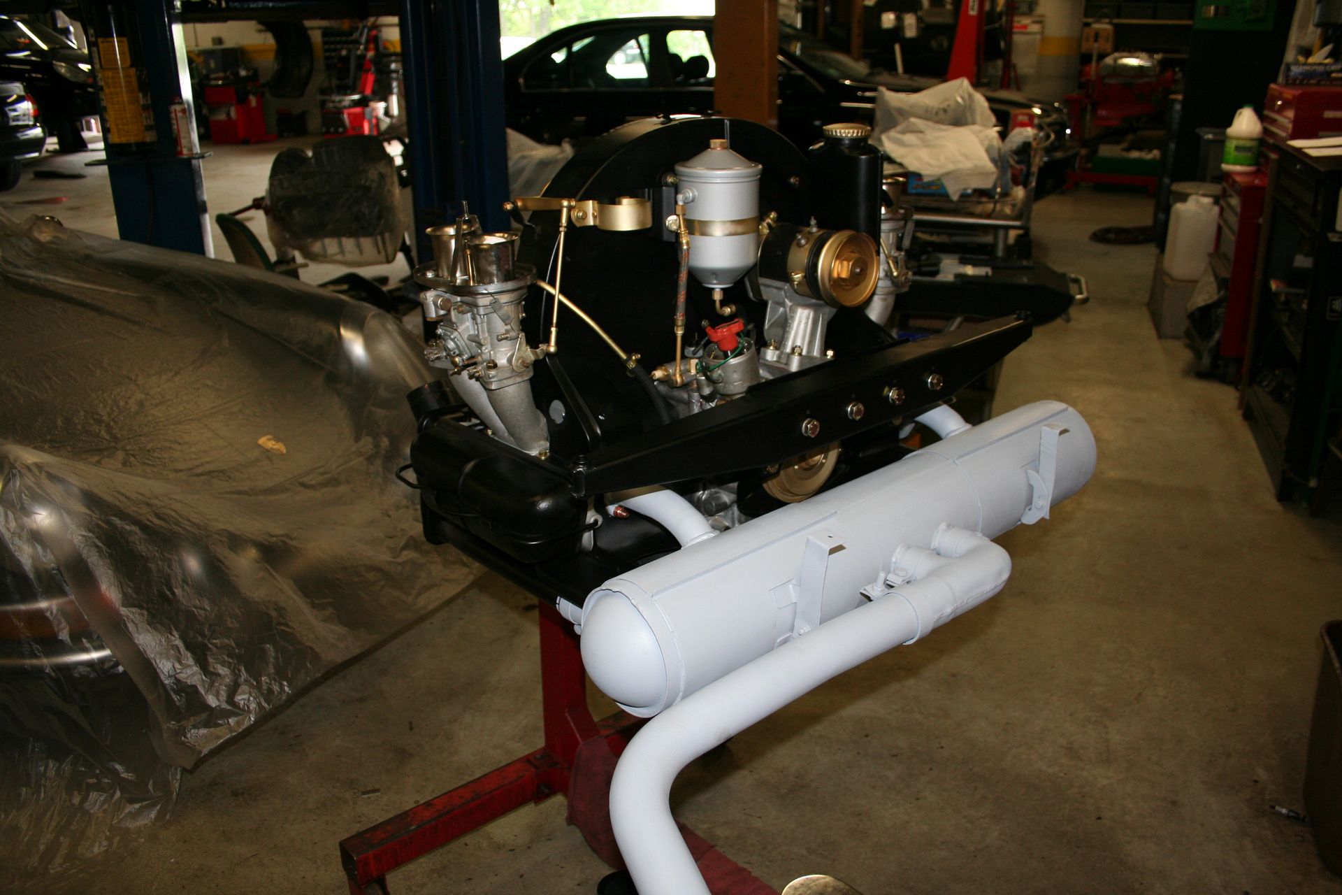 Black engine with white exhaust on a red stand in a garage. | Autobahn Performance Inc