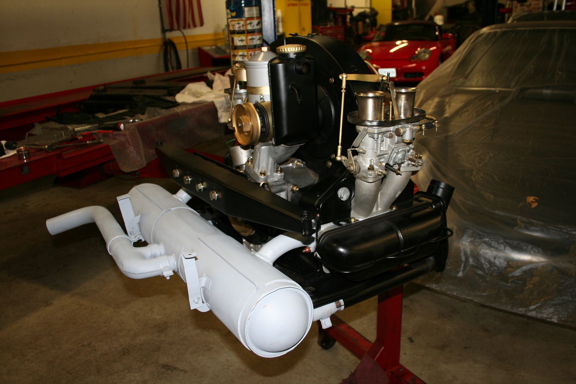 Black engine with white exhaust on a red stand, in a garage setting. | Autobahn Performance Inc