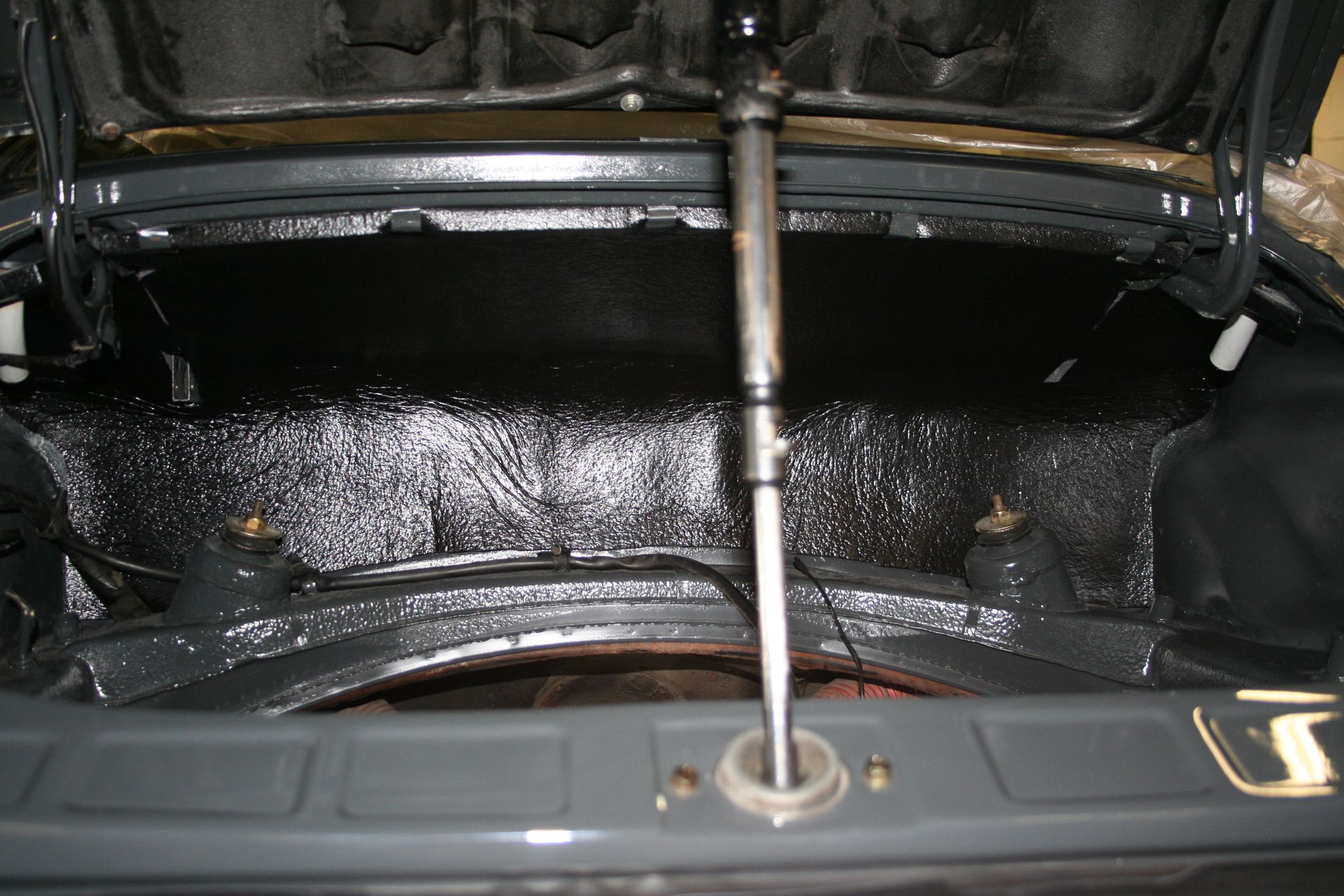 Inside of a car's trunk, covered in black material with a lift support rod in the center. | Autobahn Performance Inc