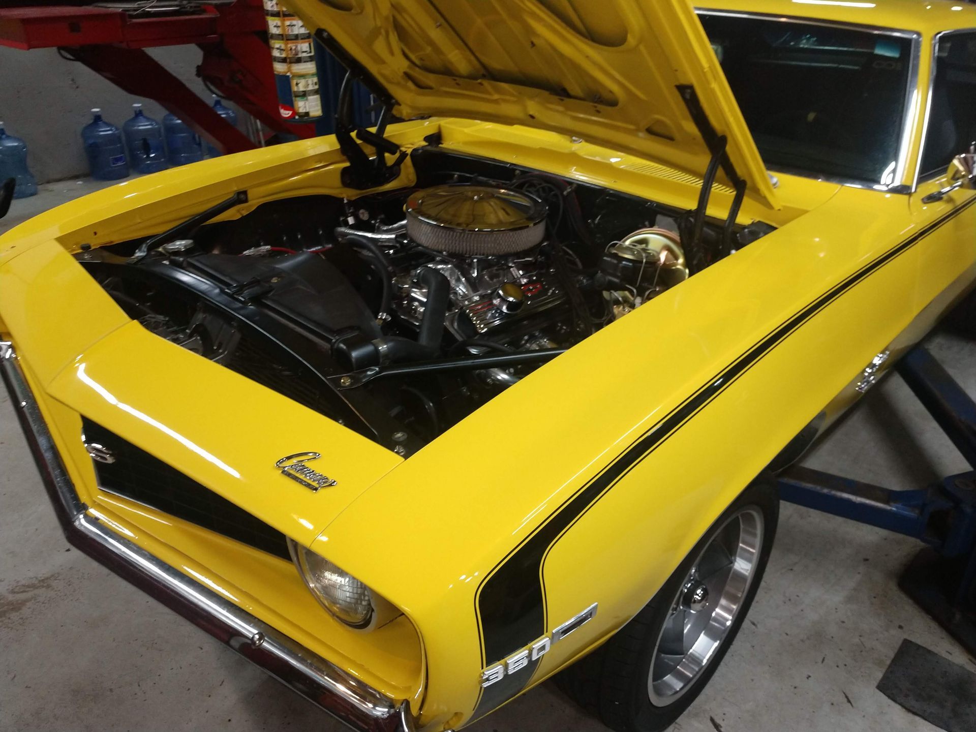 Yellow classic Chevrolet Camaro with hood up in garage. | Autobahn Performance