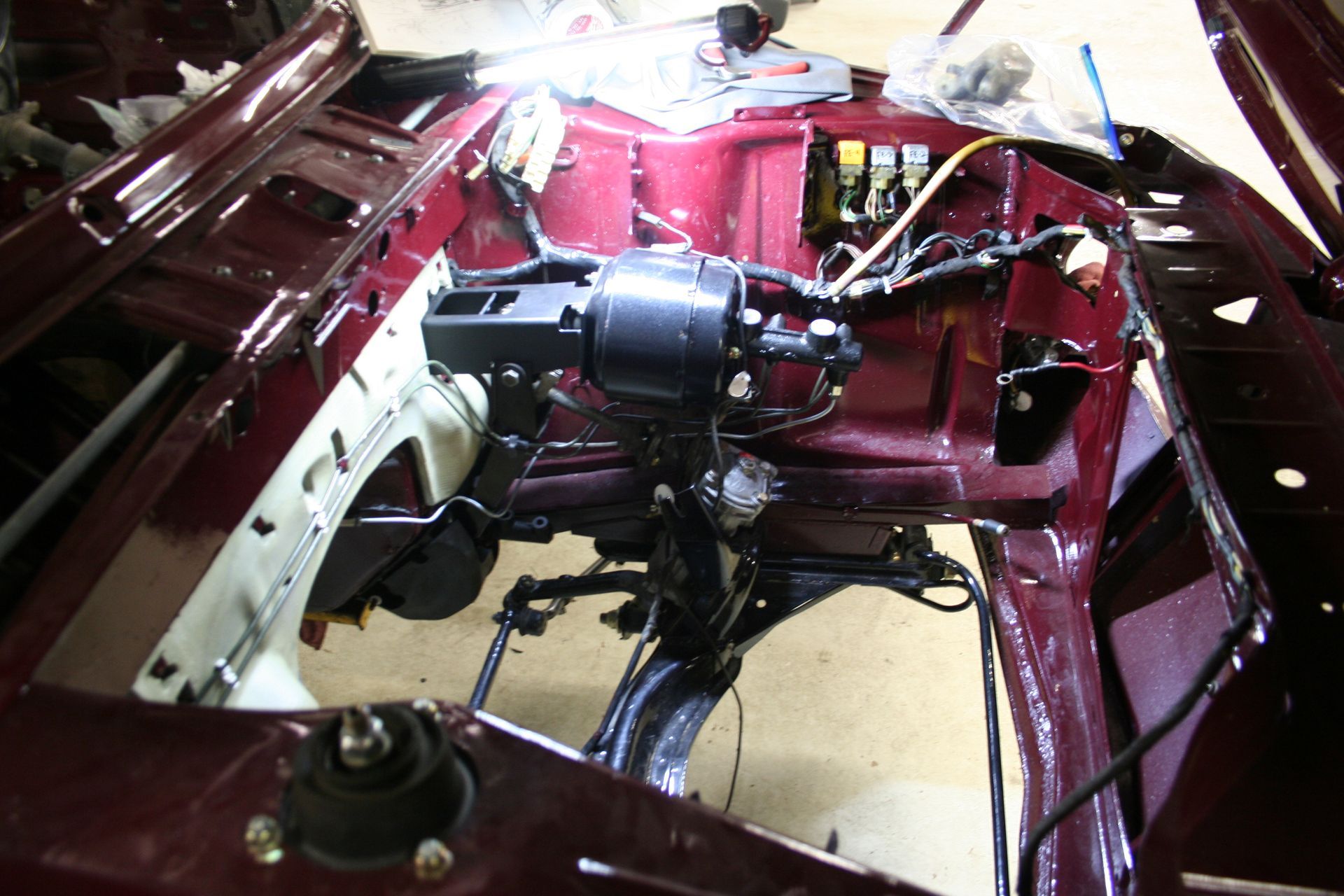 Dark red car frame with black components installed in engine bay. | Autobahn Performance Inc