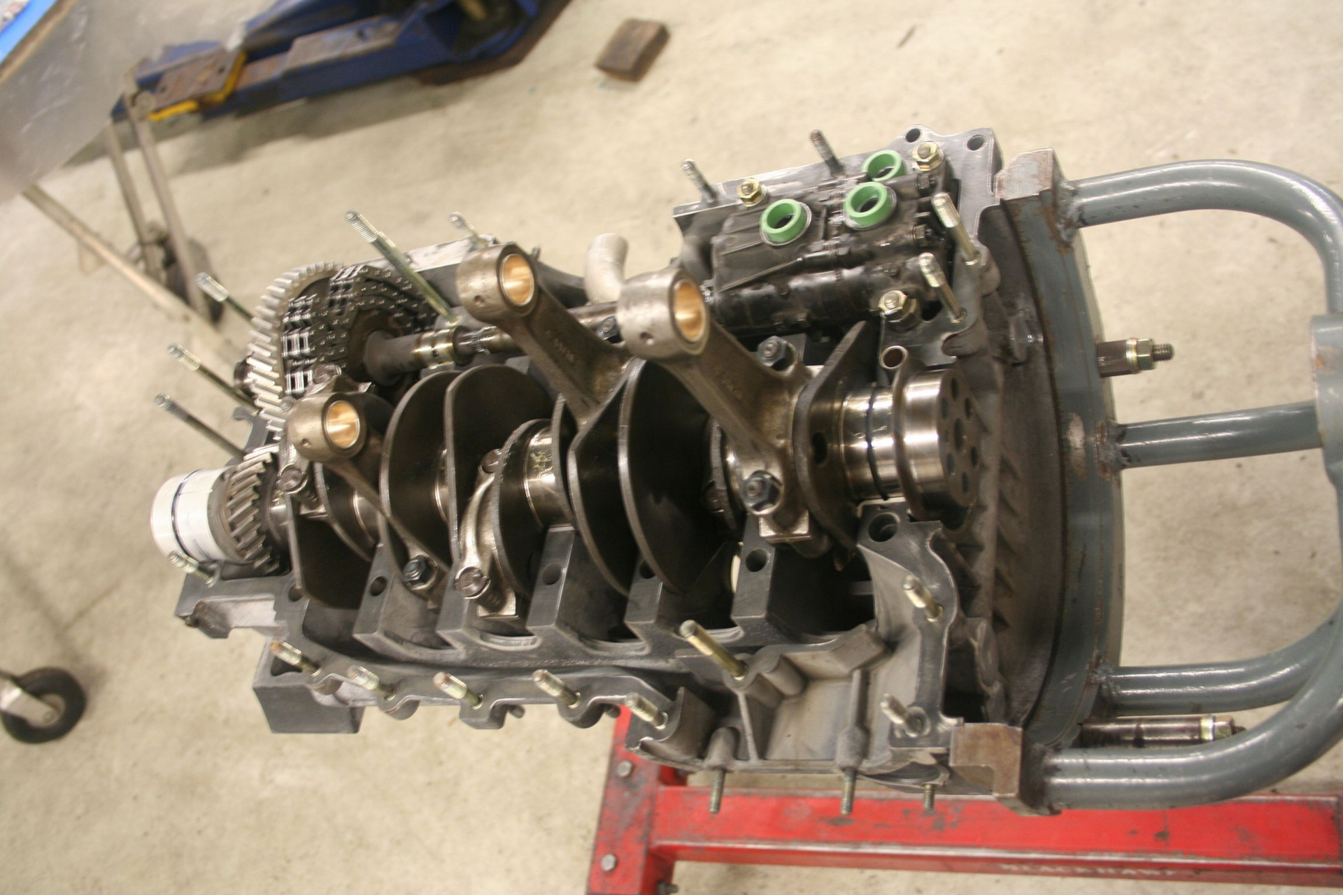 Engine block with visible crankshaft, connecting rods, and gears in a workshop setting. | Autobahn Performance Inc
