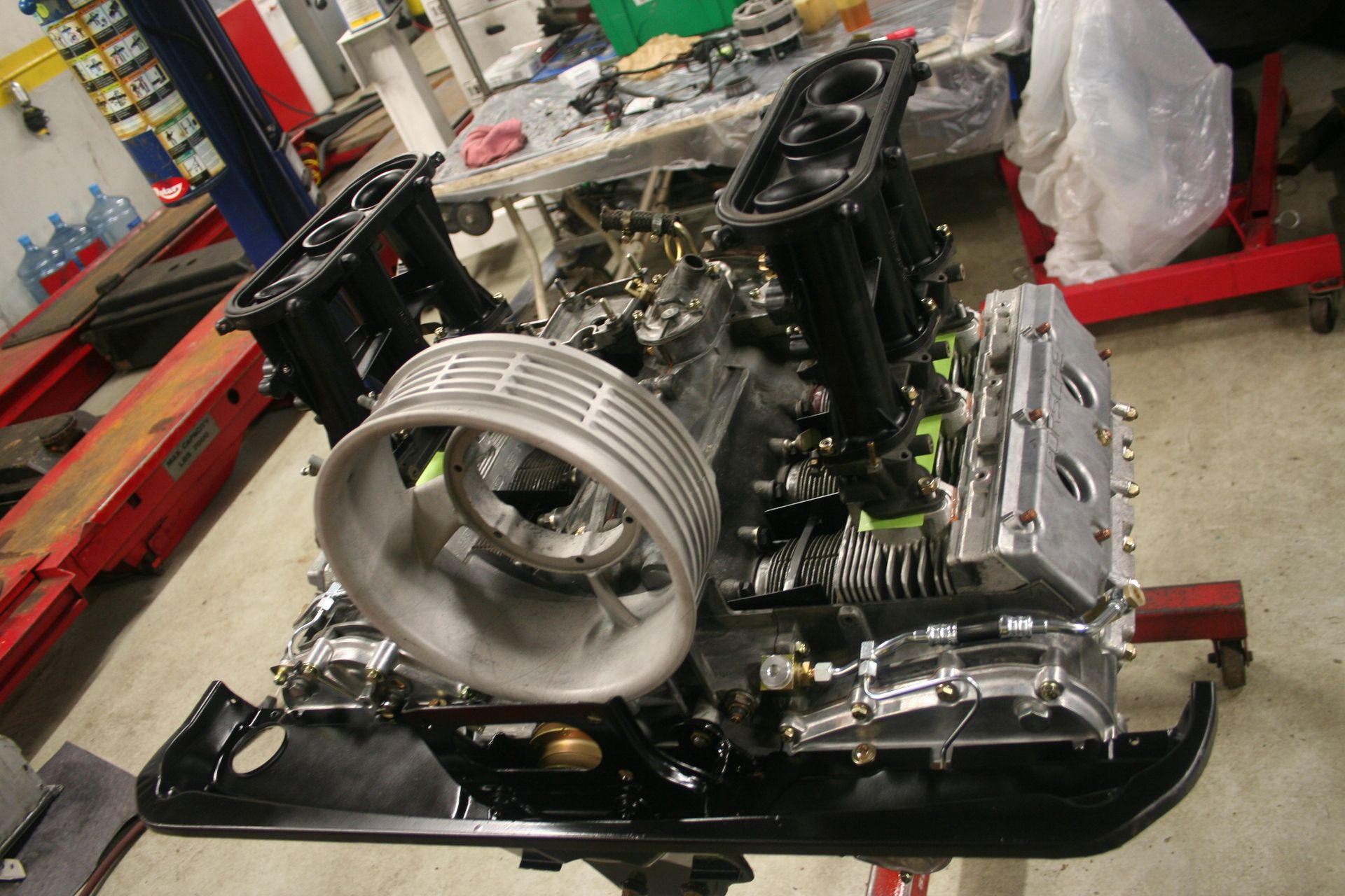 Partially assembled car engine on a stand, black, silver, and green components visible, with large air intake. | Autobahn Performance Inc