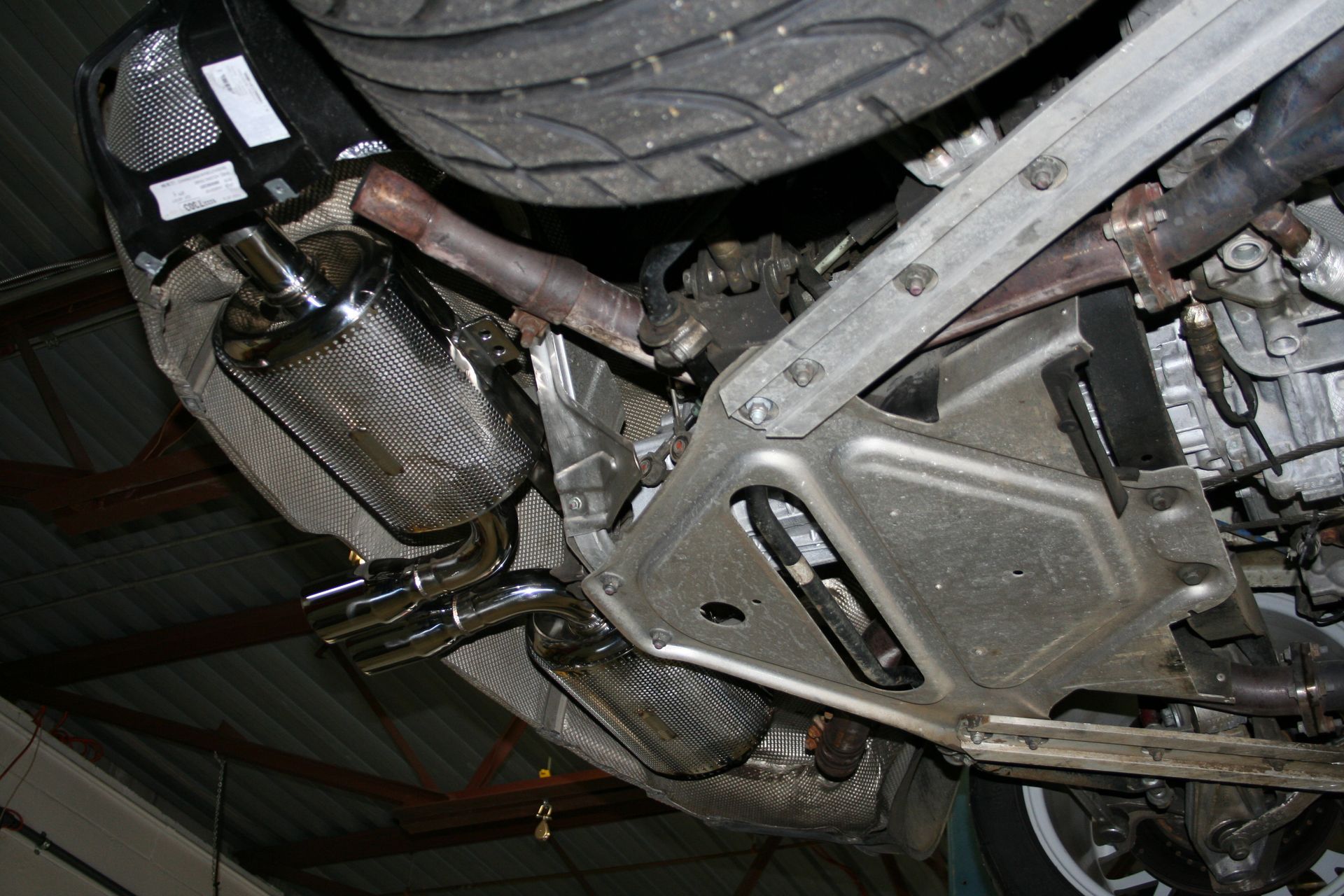 Underside of a car showing the exhaust system and mechanical components. Chrome exhaust pipes are visible. | Autobahn Performance Inc