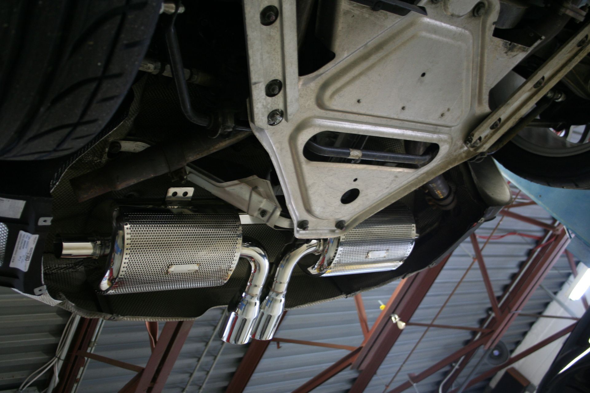 Undercarriage view of a vehicle with chrome exhaust mufflers and a silver frame. | Autobahn Performance Inc