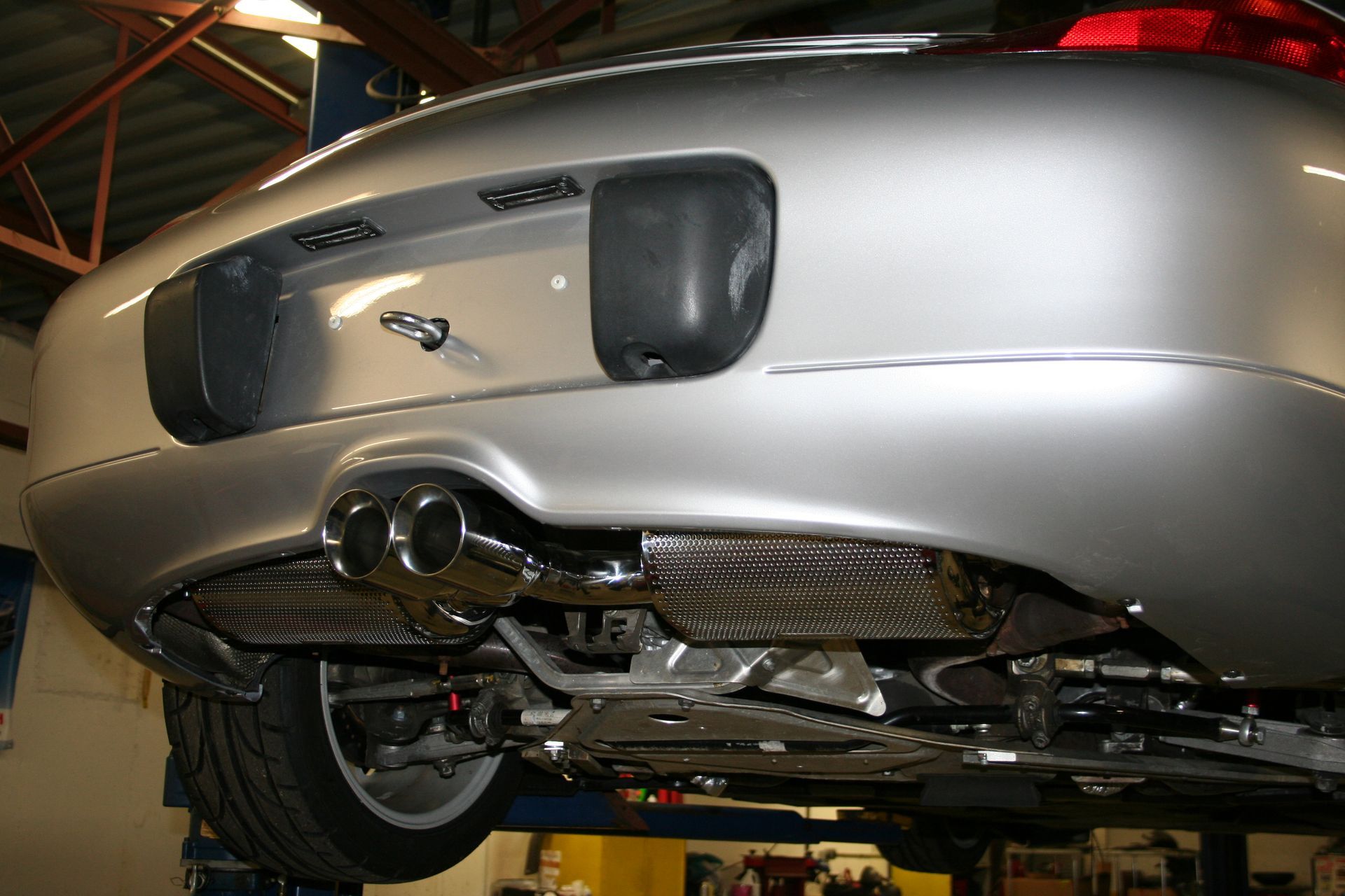 Silver car's underside view, exhaust pipes visible. The car is elevated, likely for servicing. | Autobahn Performance Inc