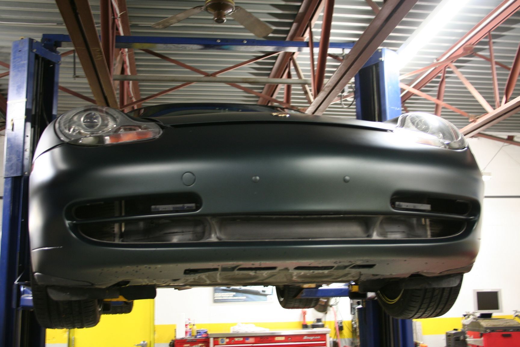 Dark-colored car on a lift in a garage. Underneath is visible. | Autobahn Performance Inc