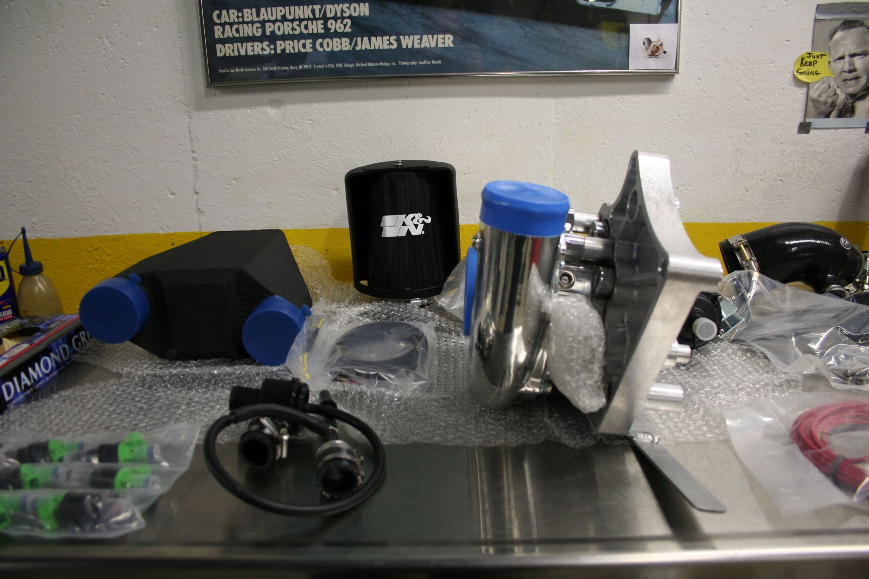 Car engine parts: intake manifold, air filter, and turbocharger on a workbench. | Autobahn Performance Inc