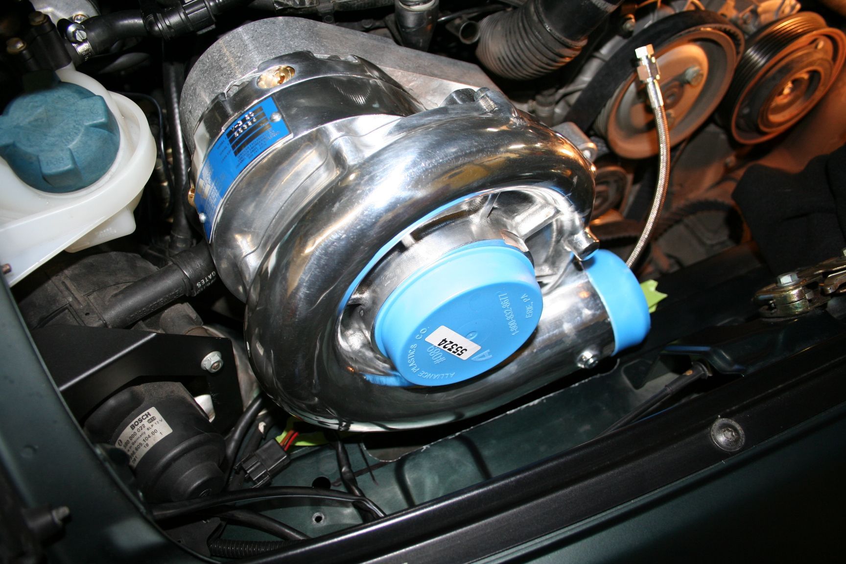 Supercharger engine installed in a car engine bay, with blue and silver components. | Autobahn Performance Inc