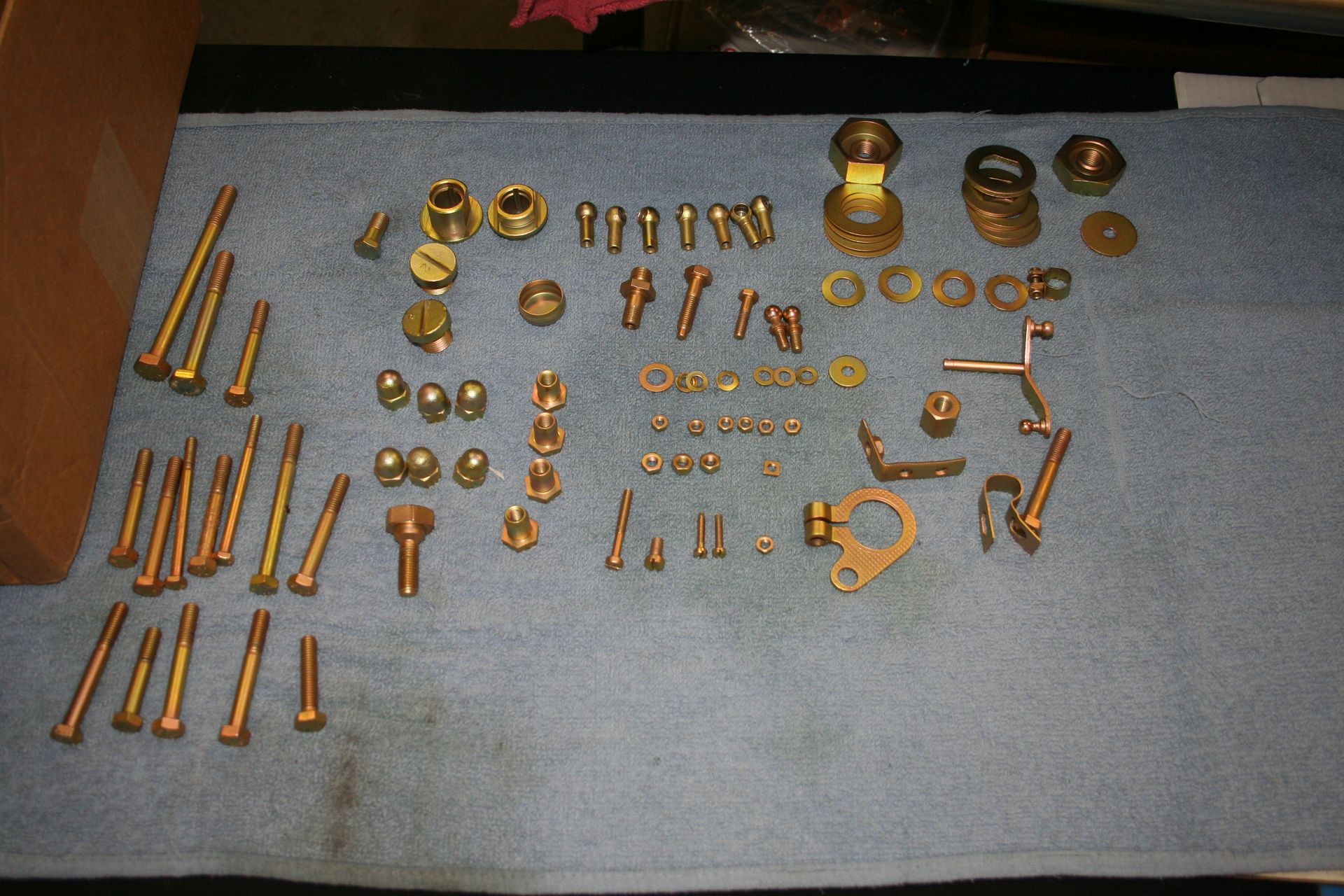 Brass carburetor parts neatly arranged on a blue cloth. | Autobahn Performance Inc