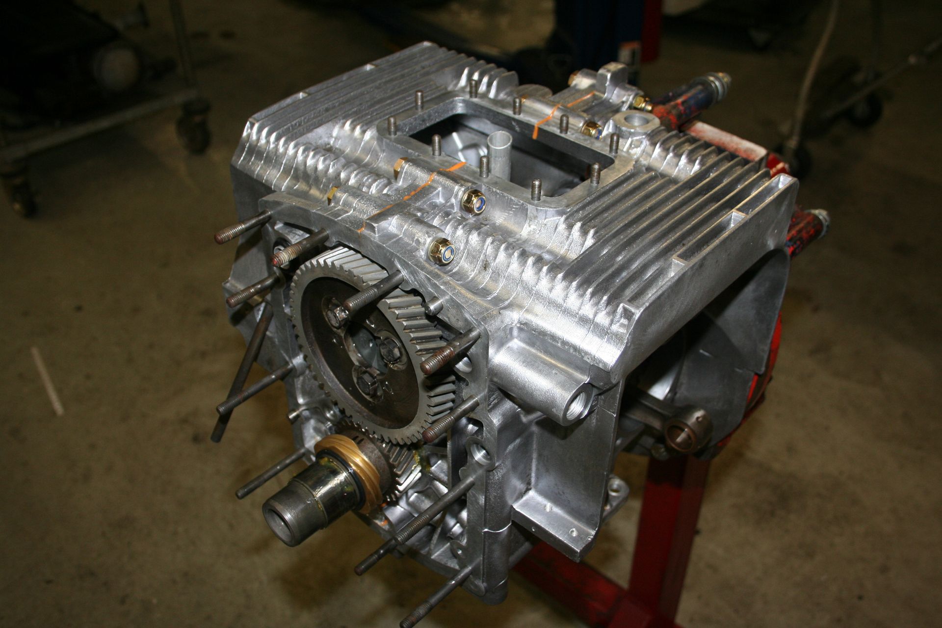 Partially assembled silver engine on a red stand; exposed gears and cooling fins are visible. | Autobahn Performance Inc