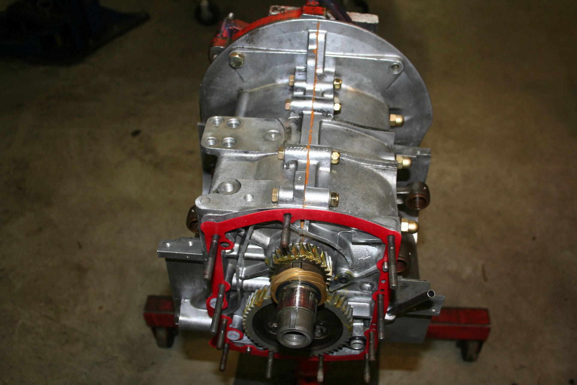 Close-up of a disassembled metallic car transmission with red gasket visible; resting on a support. | Autobahn Performance Inc