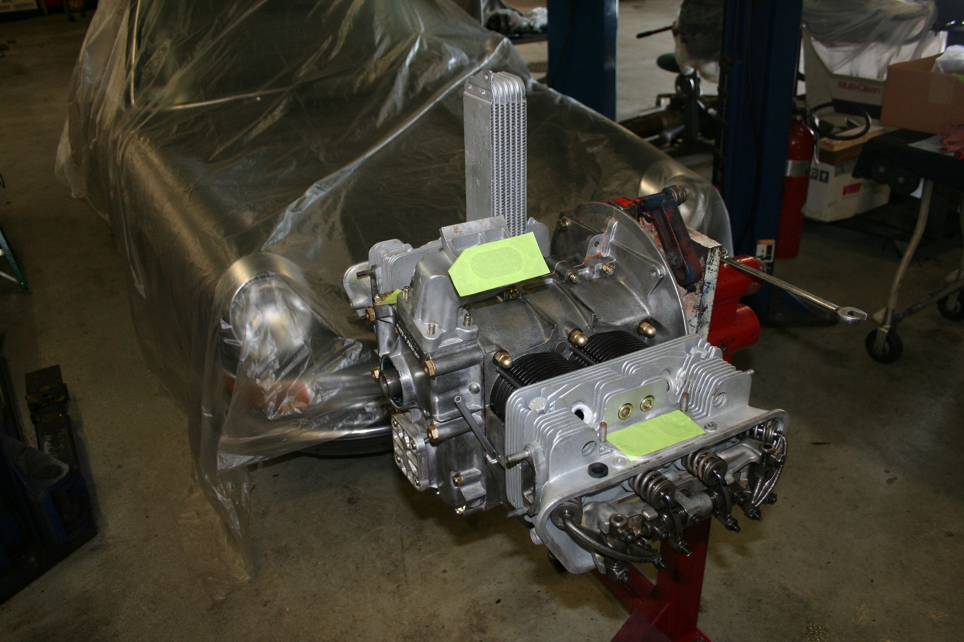 Engine on stand in front of covered car, likely in a garage. | Autobahn Performance Inc