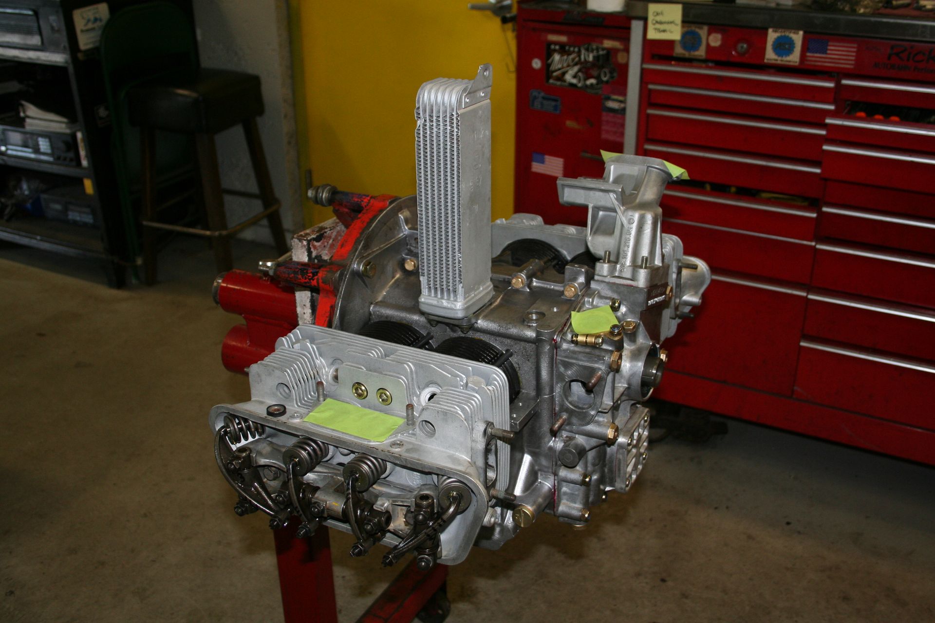 A partially assembled engine with a silver cooling system, on a red stand, in a workshop. | Autobahn Performance Inc