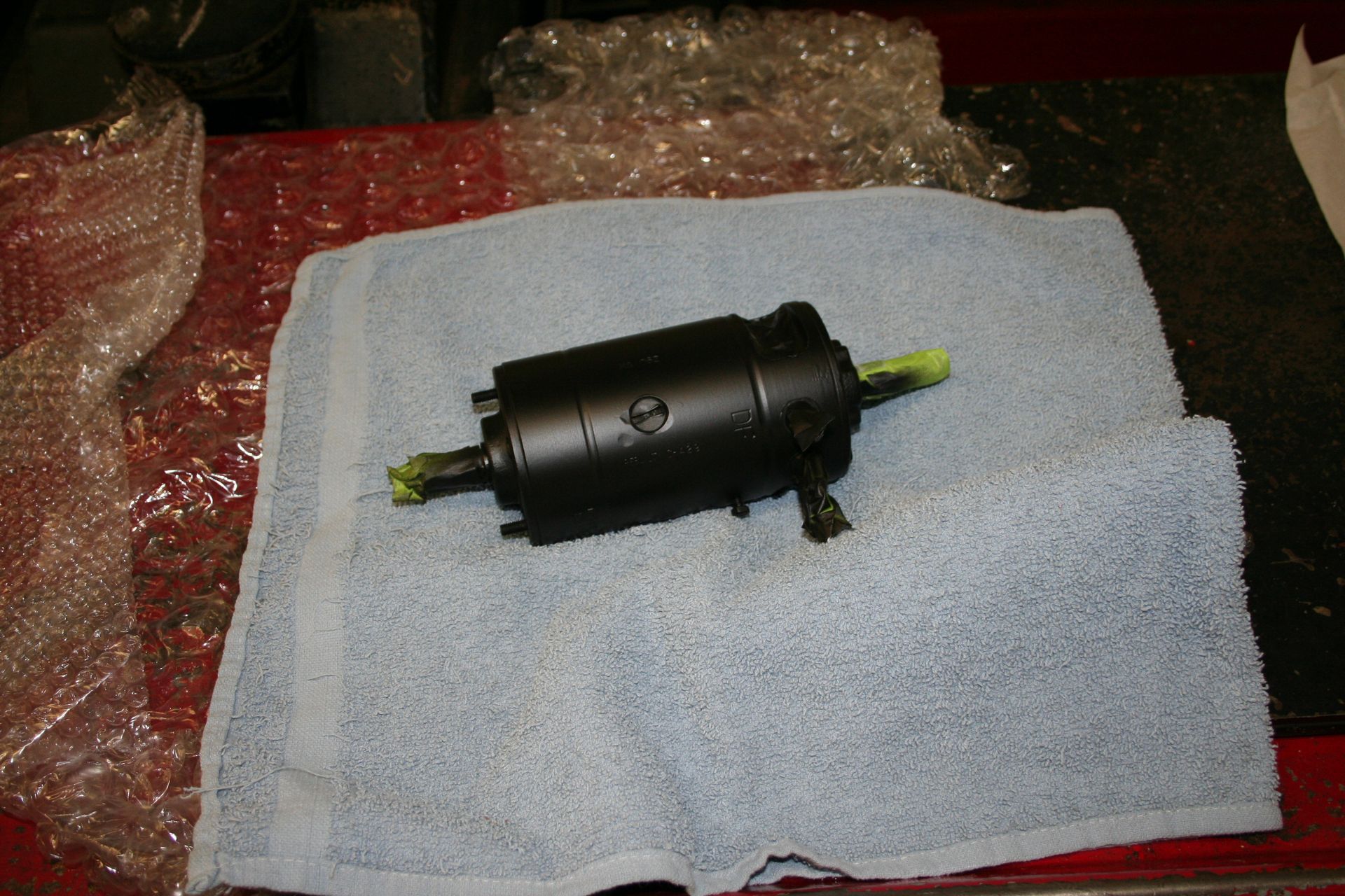 Black cylindrical object on a blue towel, with green tape on either end. | Autobahn Performance Inc