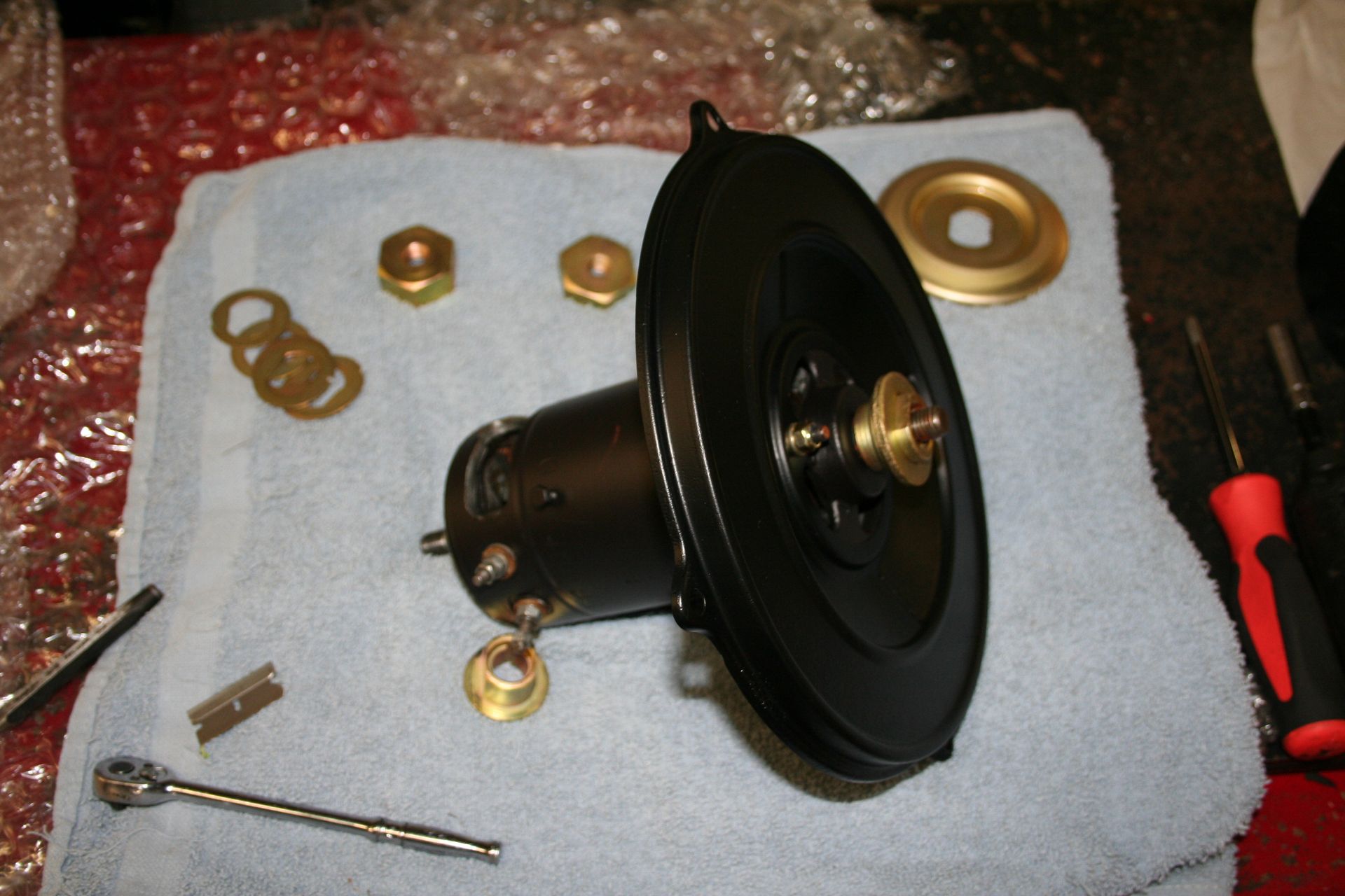 Black painted motor with brass fittings and washers, on a blue towel. Tools scattered around. | Autobahn Performance Inc