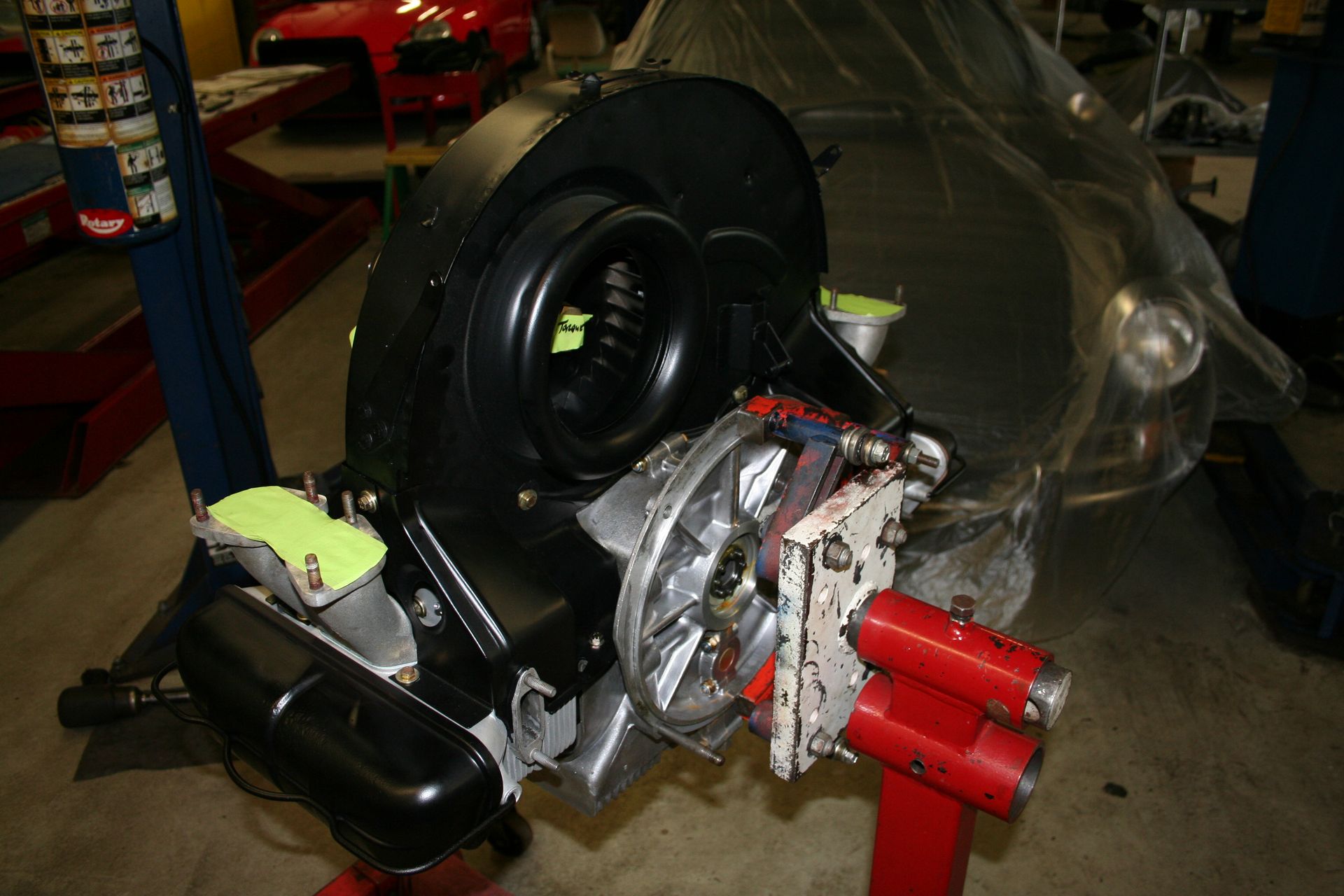 Black car engine assembly on a red stand. Partially assembled with some parts attached. Garage setting. | Autobahn Performance Inc