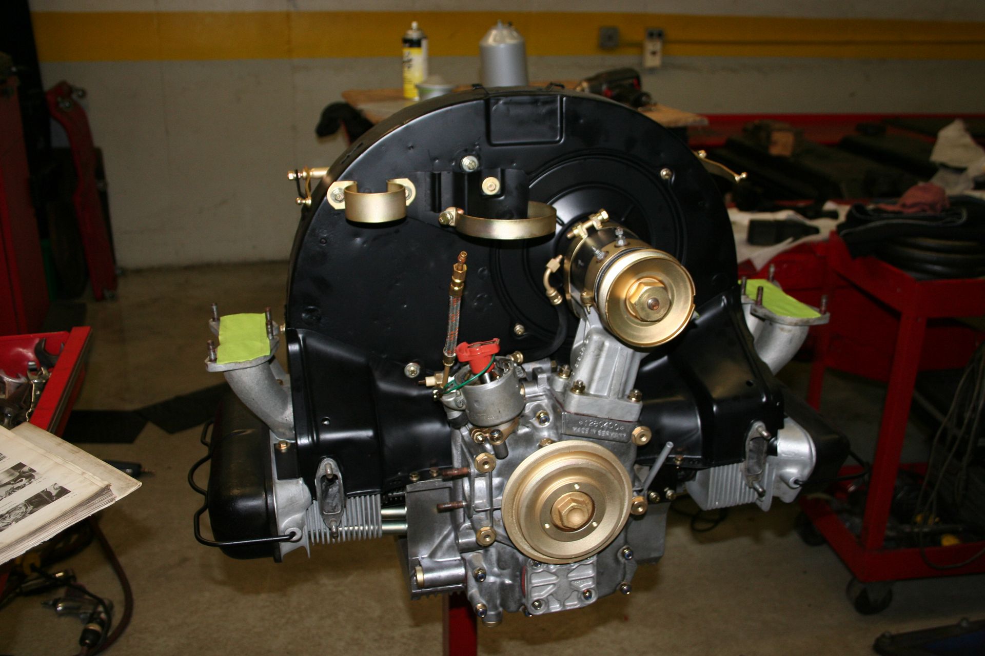 Black Volkswagen engine on a stand, with gold accents and a silver block in a shop. | Autobahn Performance Inc