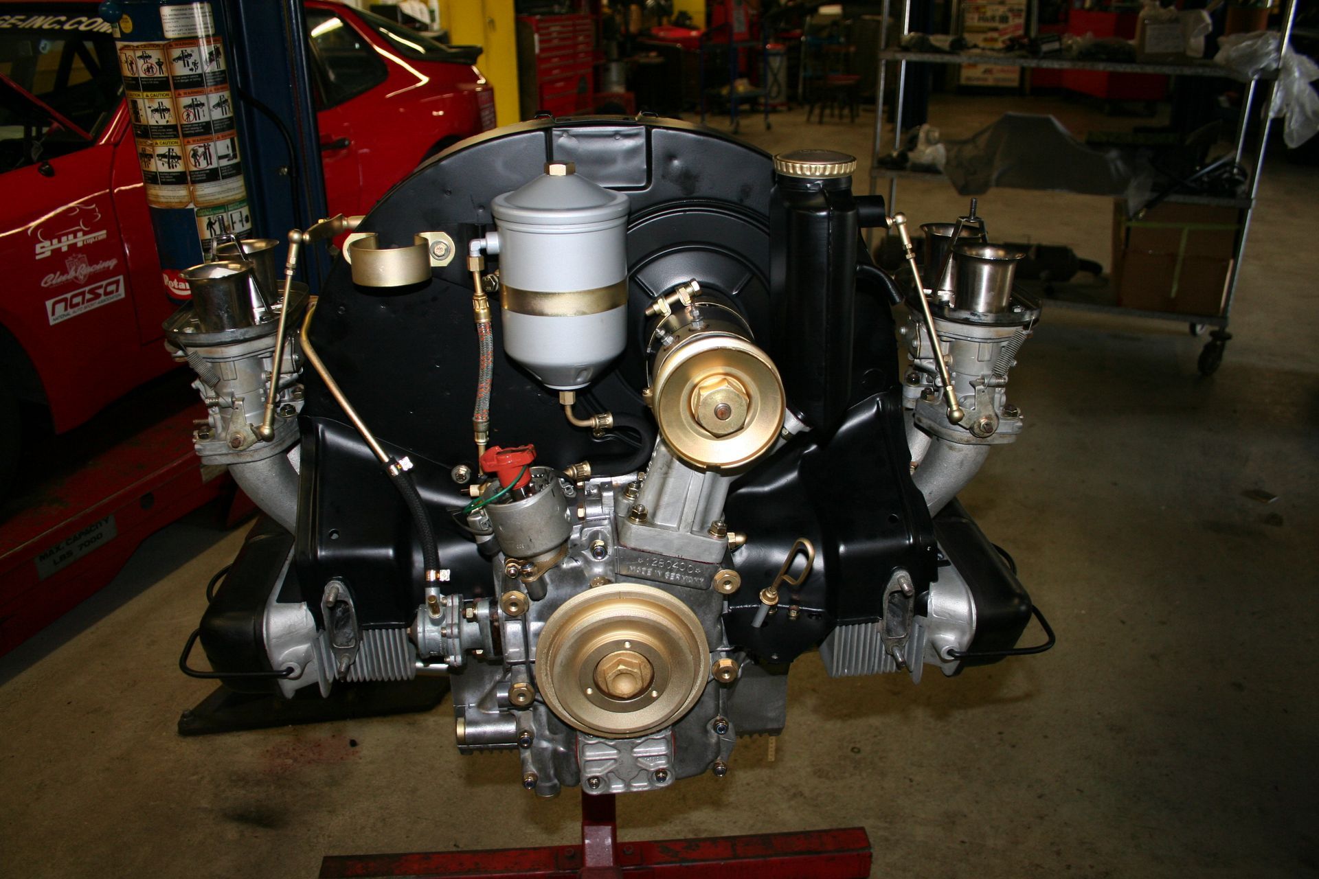 Volkswagen Beetle engine, black with gold and silver components, on a red stand. | Autobahn Performance Inc