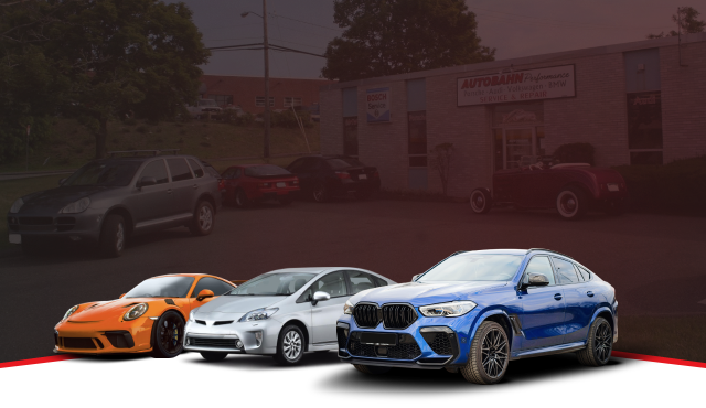 Red Dodge Challenger in front of an auto shop, with cars in the background. | Autobahn Performance Inc