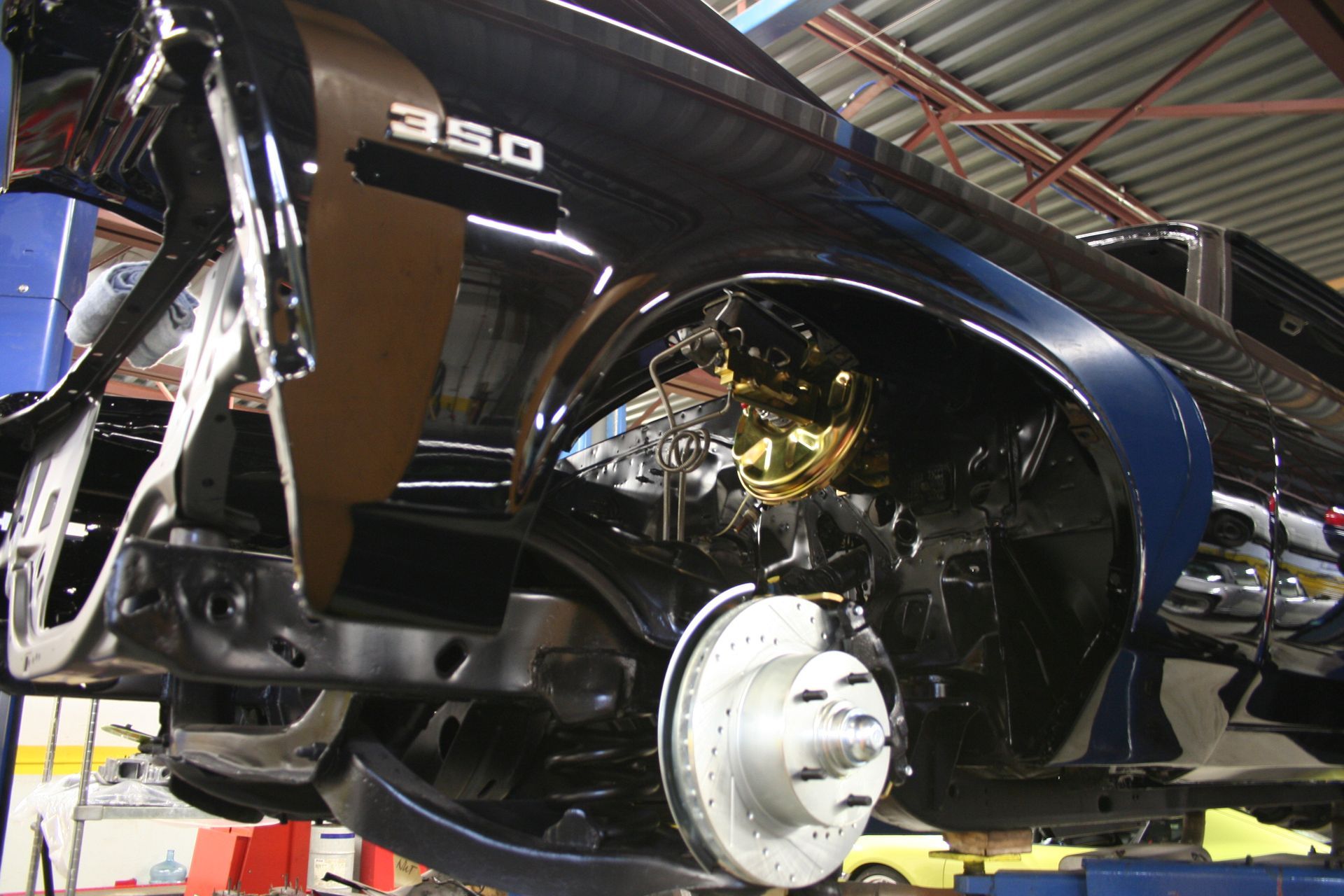 Black classic car restoration in progress, revealing engine components and disc brakes. | Autobahn Performance Inc