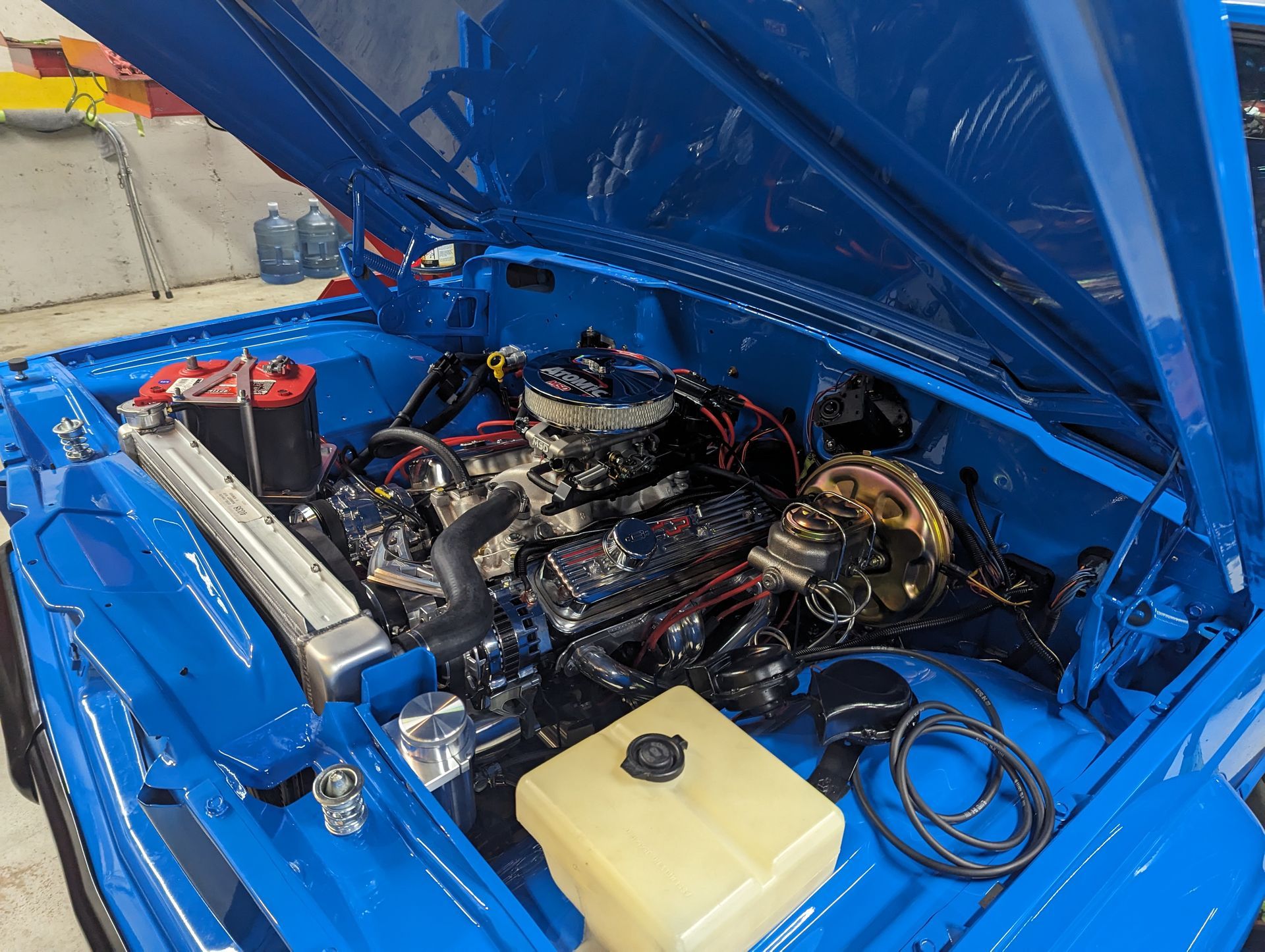 Bright blue car engine bay with a chrome engine, black wiring, and a yellow fluid tank. | Autobahn Performance