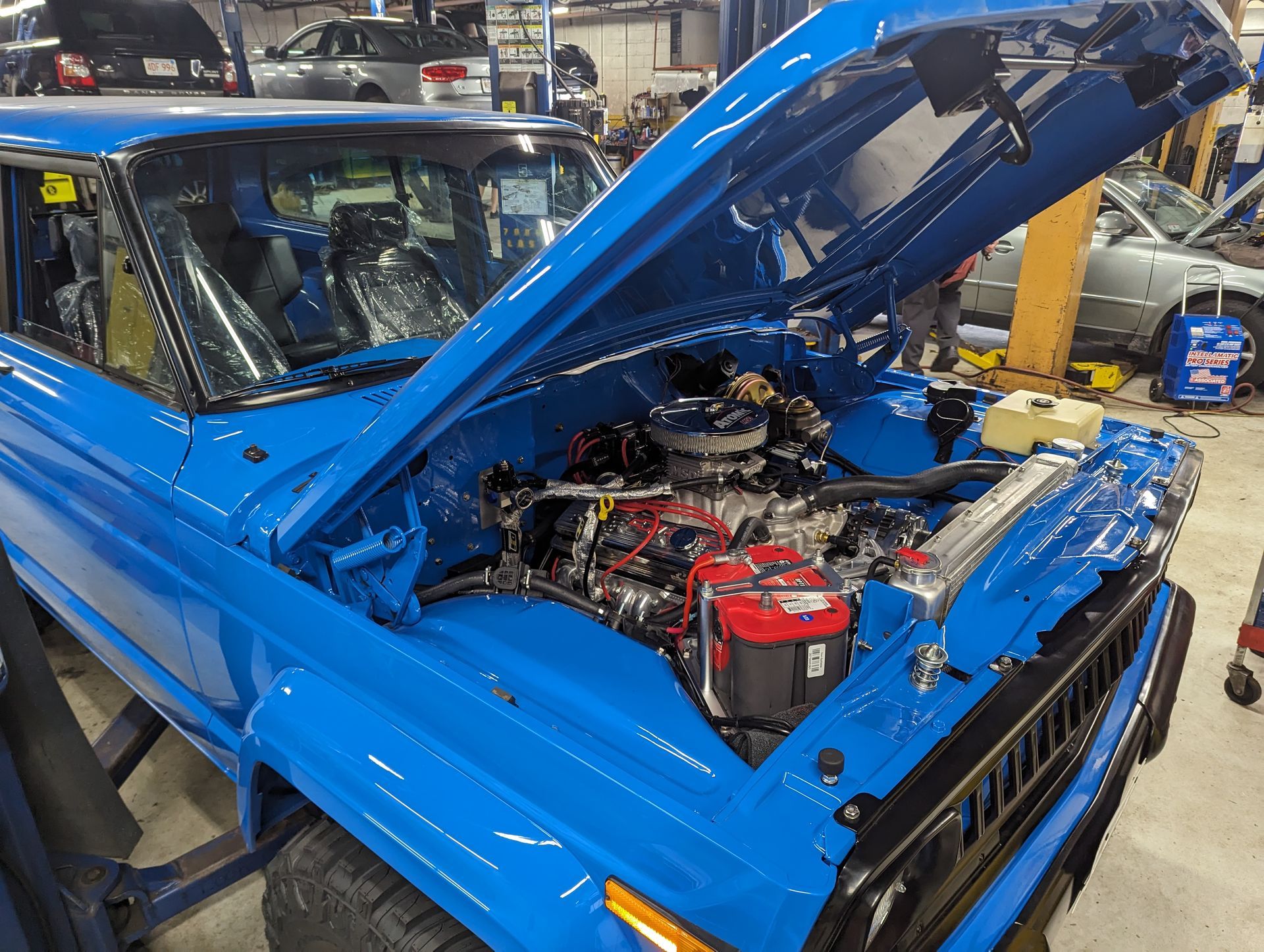 Bright blue classic Jeep with hood open, showing engine. Inside a garage. | Autobahn Performance