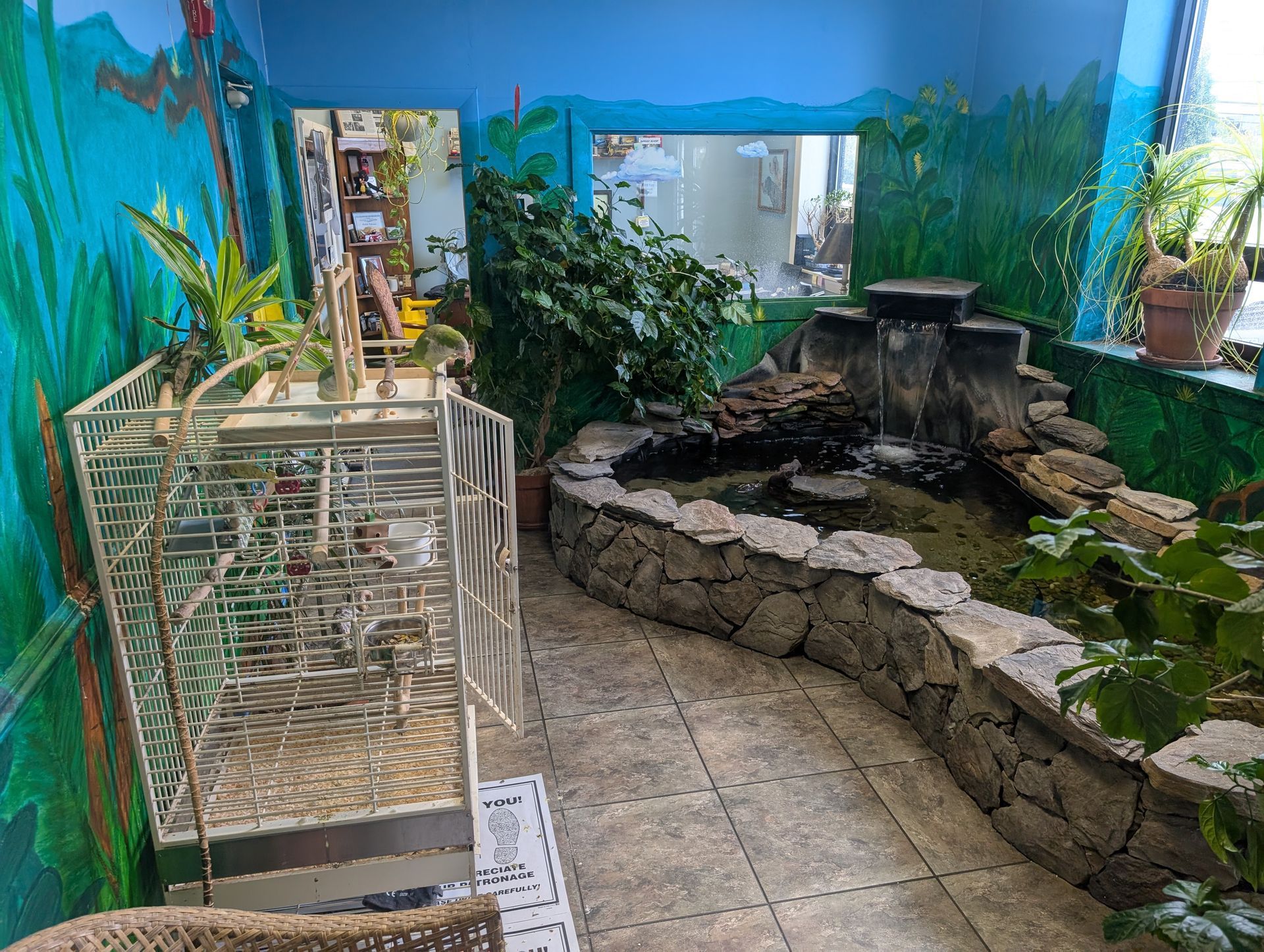 Indoor pond and garden area with waterfall, greenery, and painted walls. | Autobahn Performance Inc