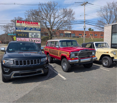 Three Jeeps parked in front of a business: a black Grand Cherokee, a red Grand Wagoneer, and a yellow Wrangler. | Autobahn Performance Inc