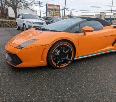 Orange Lamborghini convertible with black rims, parked outside a business. | Autobahn Performance Inc