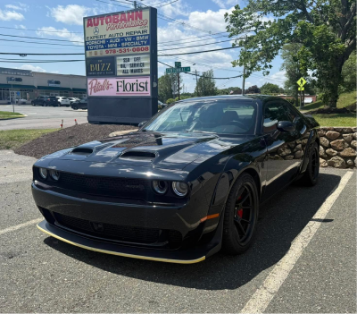 Black Dodge Challenger parked near a business sign on a sunny day. | Autobahn Performance Inc