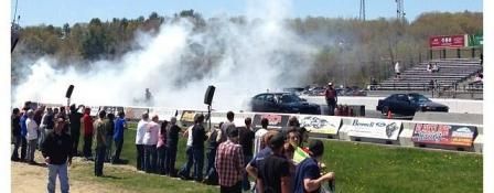 Drag race with cars creating smoke, spectators watching. | Autobahn Performance Inc