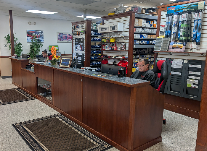 A car parts store interior with a long wooden counter, employees, and merchandise on shelves. | Autobahn Performance Inc