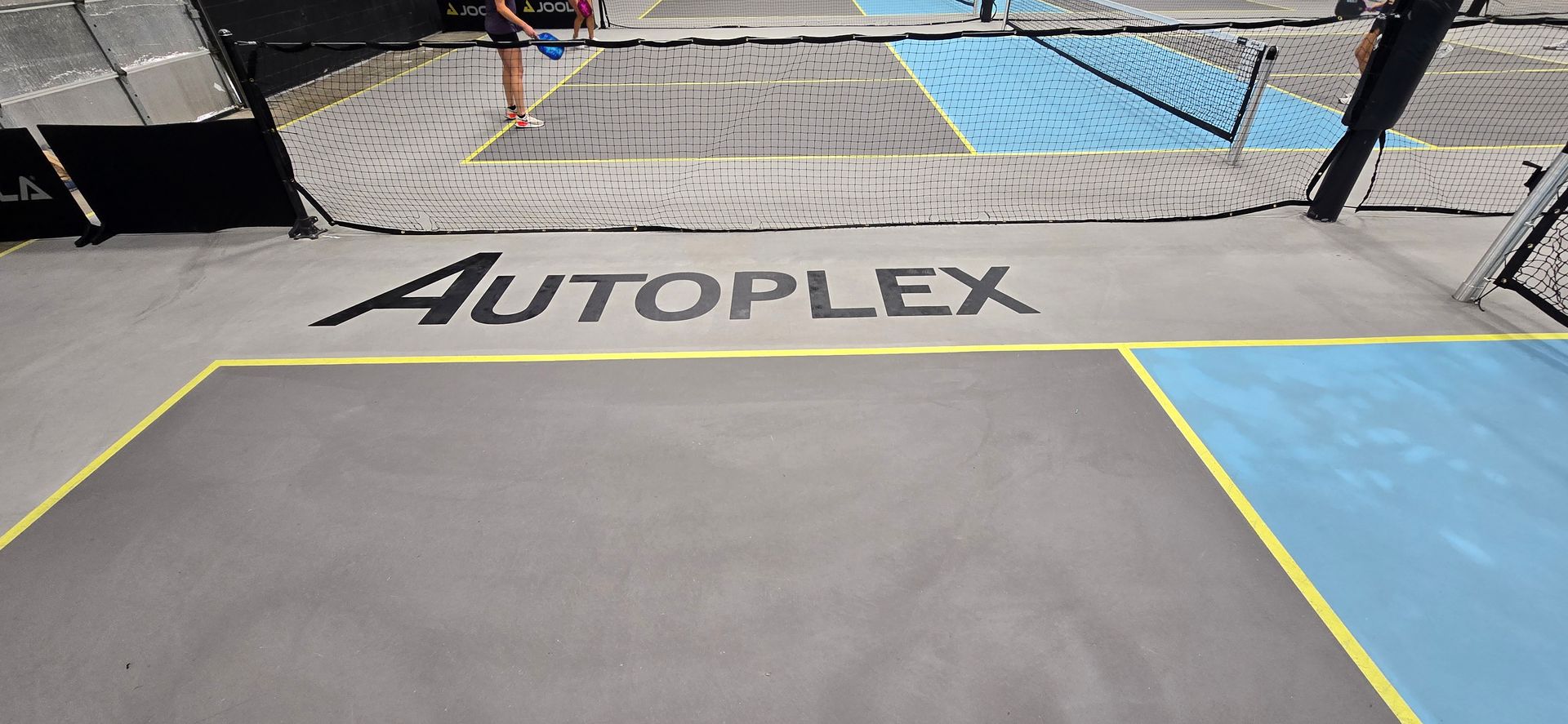 A tennis court with the word autoplex on the floor.