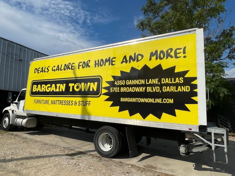A bargain town truck is parked in front of a building