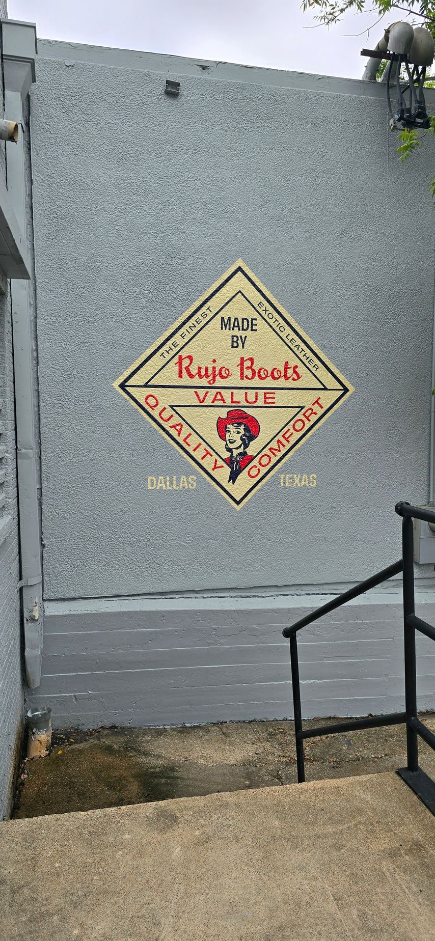 A sign on the side of a building with stairs leading up to it.