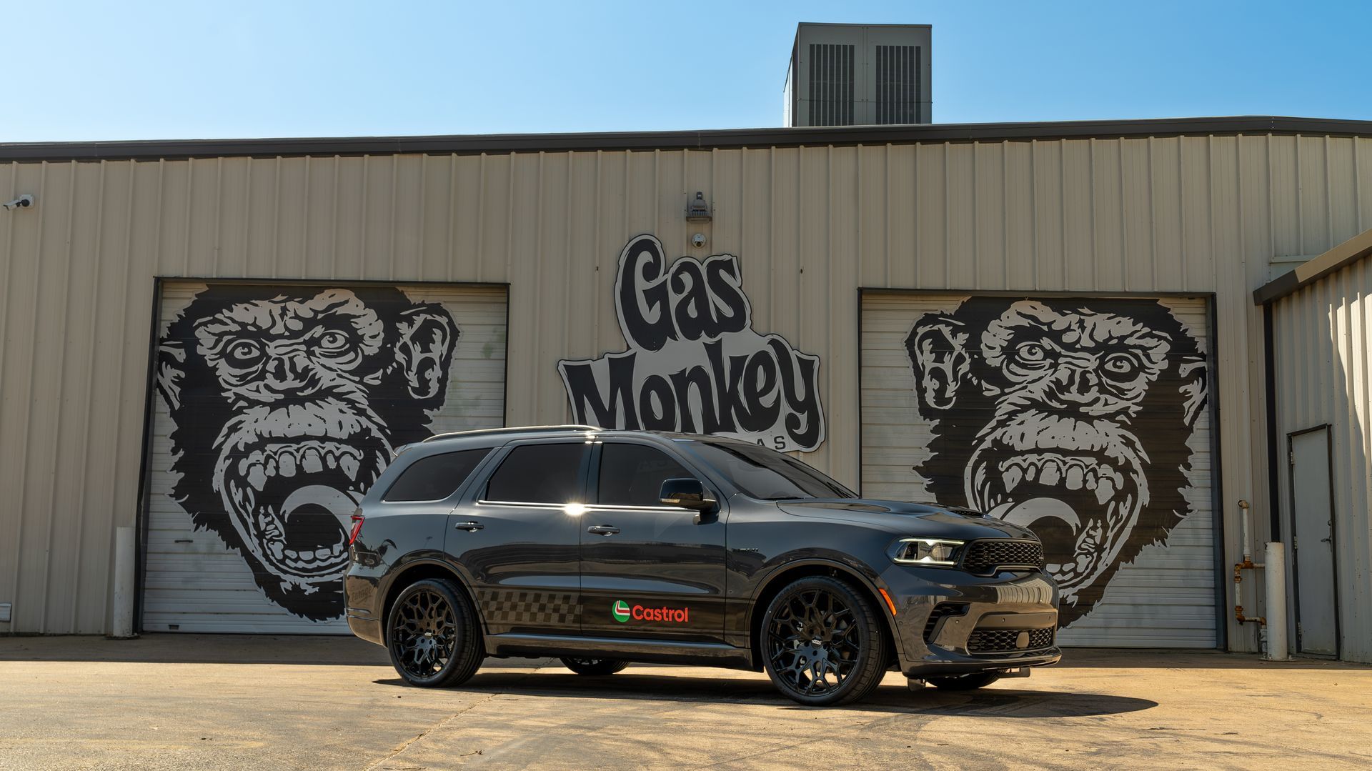A car is parked in front of a gas monkey garage.