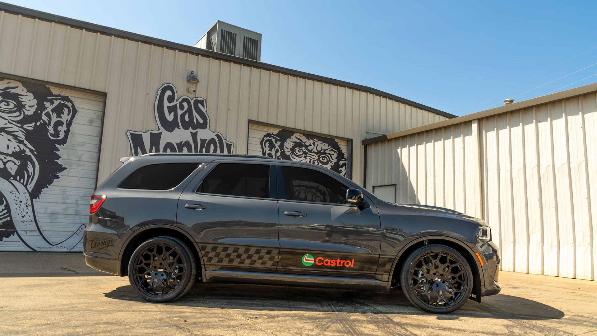 A black dodge durango is parked in front of a building with graffiti on it.