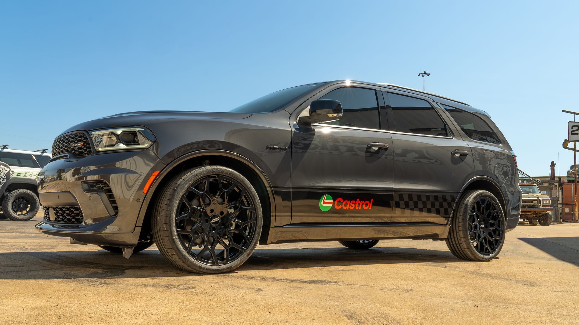 A black dodge durango is parked in a dirt lot.